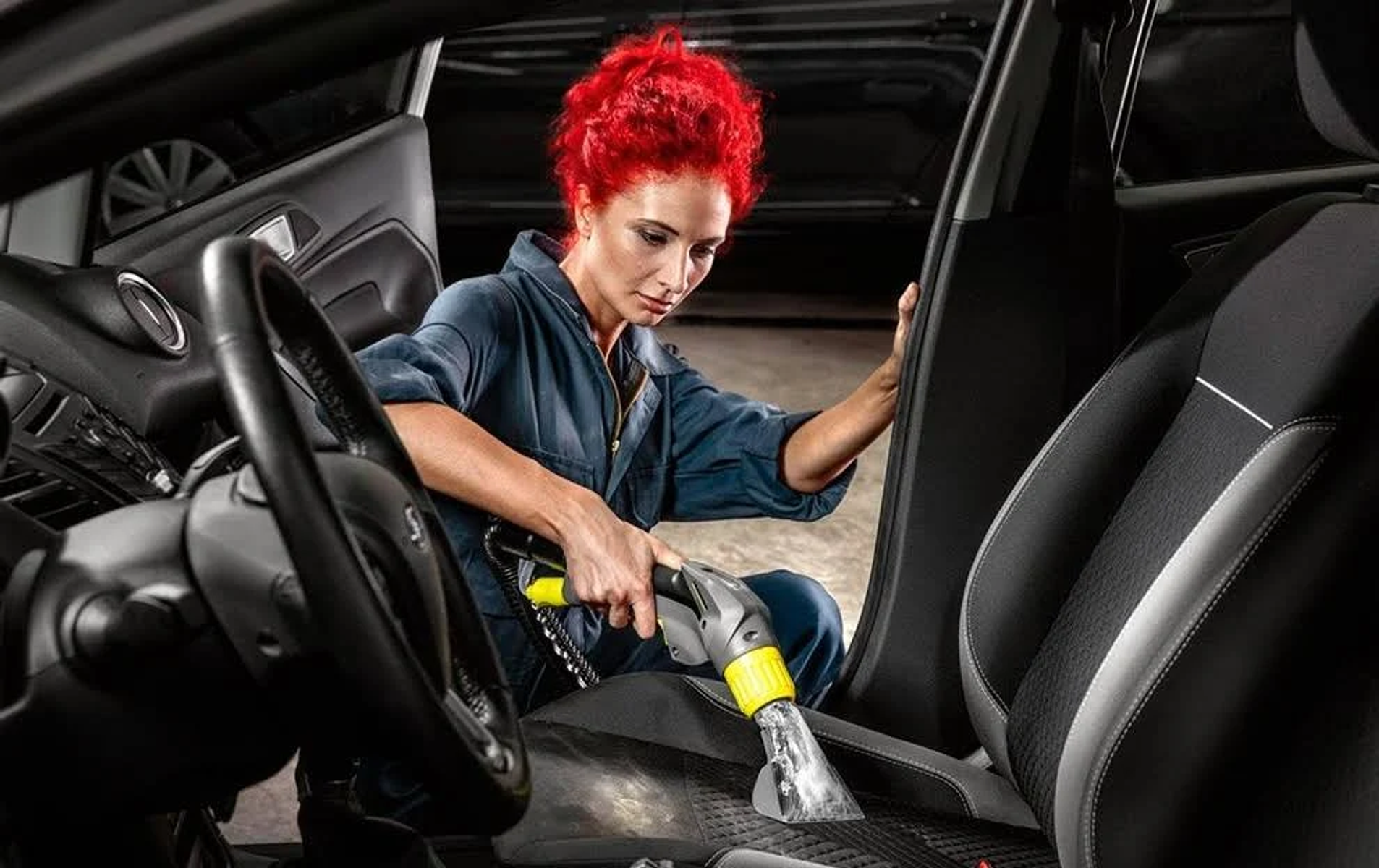 Mujer limpiando asiento de coche con aspiradora de mano.