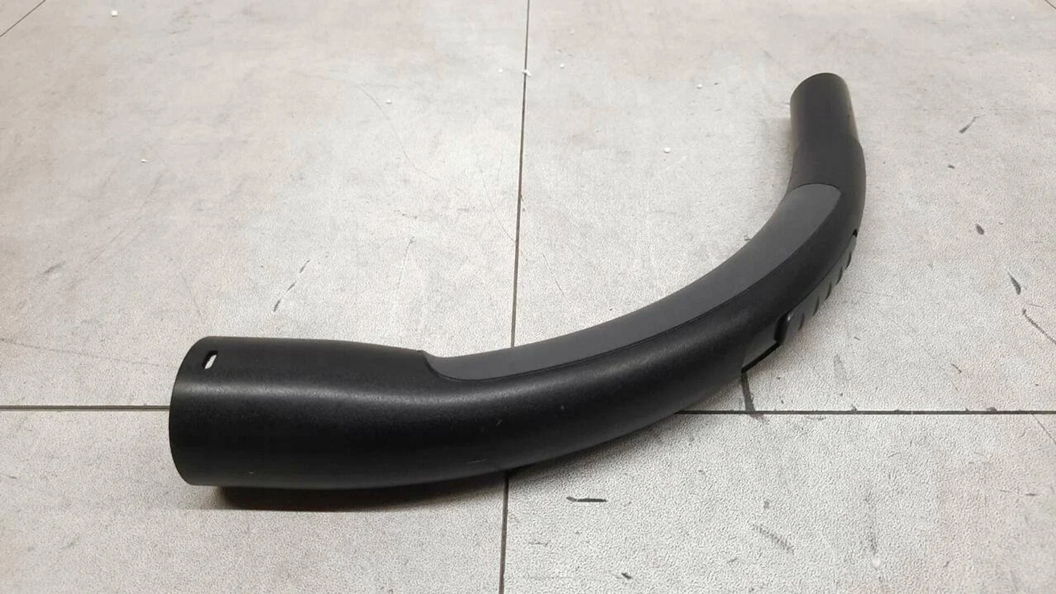 Maniglia nera curva per aspirapolvere, con sezione di presa grigia.