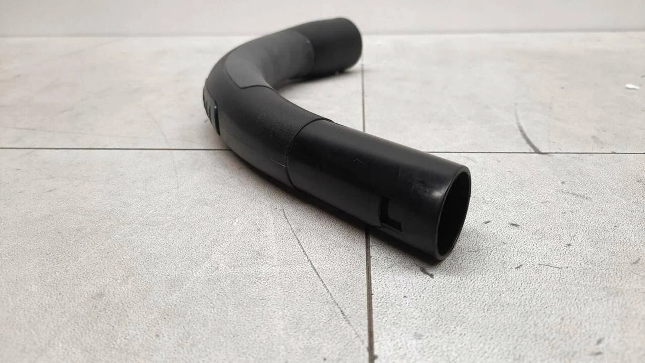 Tubo flessibile nero per aspirapolvere su bianco.