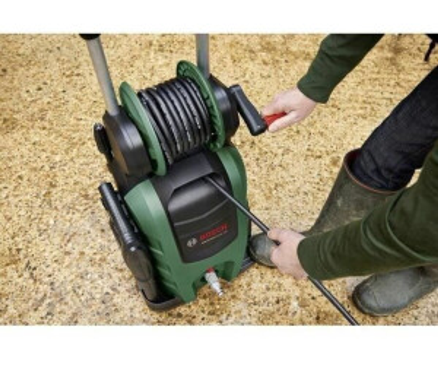 Idropulitrice Bosch. Verde e nero. Avvolgitubo e maniglia. Uomo che usa il tubo.