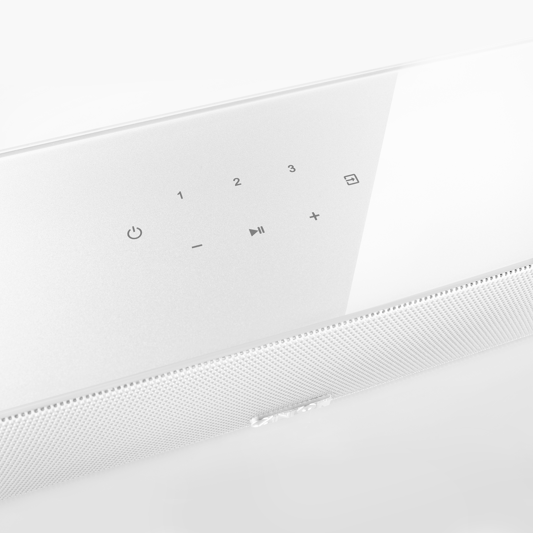 Barre de son blanche avec boutons de contrôle et grille de haut-parleur perforée, sur une surface blanche.