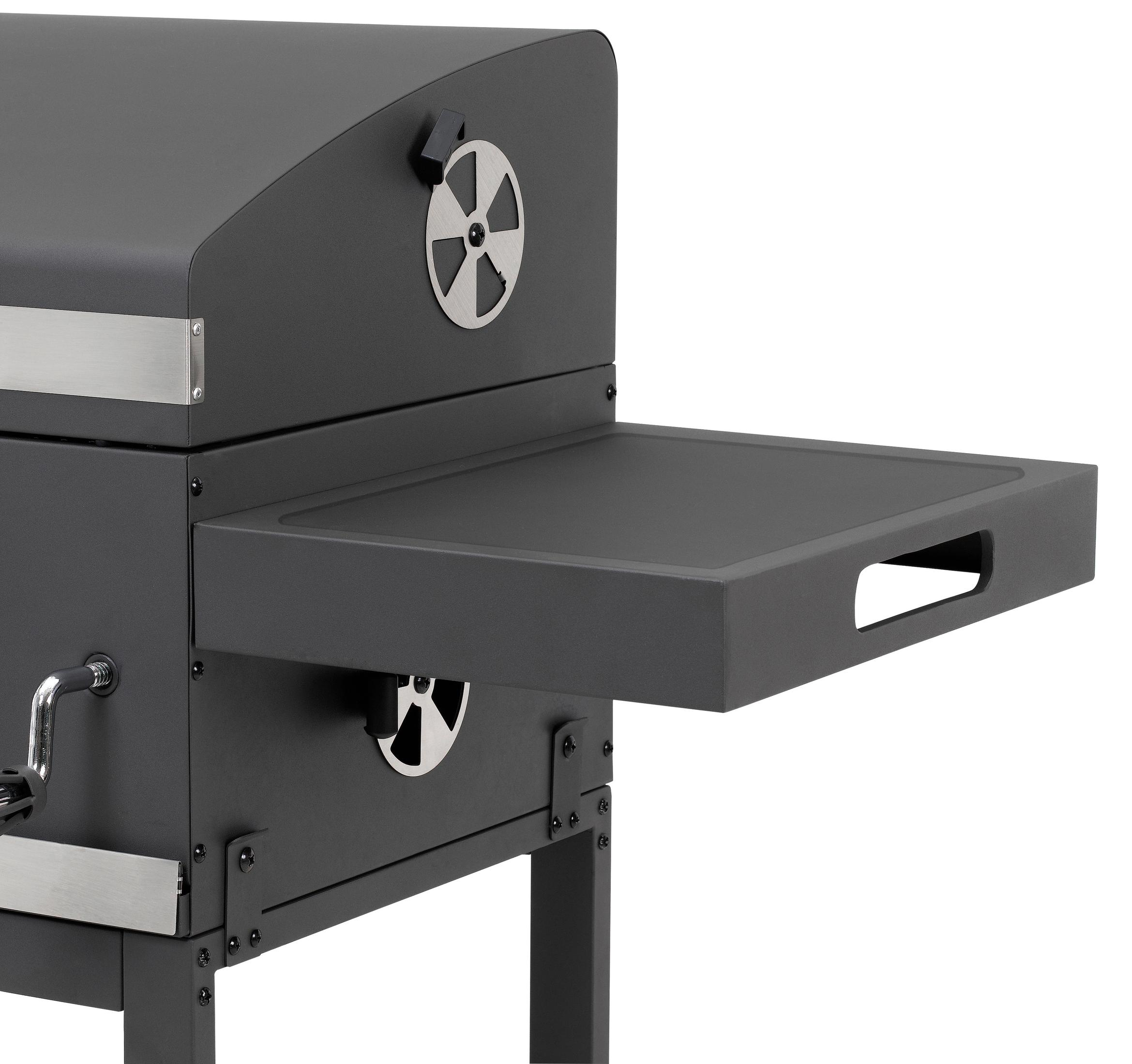 Ein dunkelgrauer Grill mit einem Seitentisch ist abgebildet. Das Regal ist ausgezogen. Ein silbernes Metalldetail ist sichtbar.