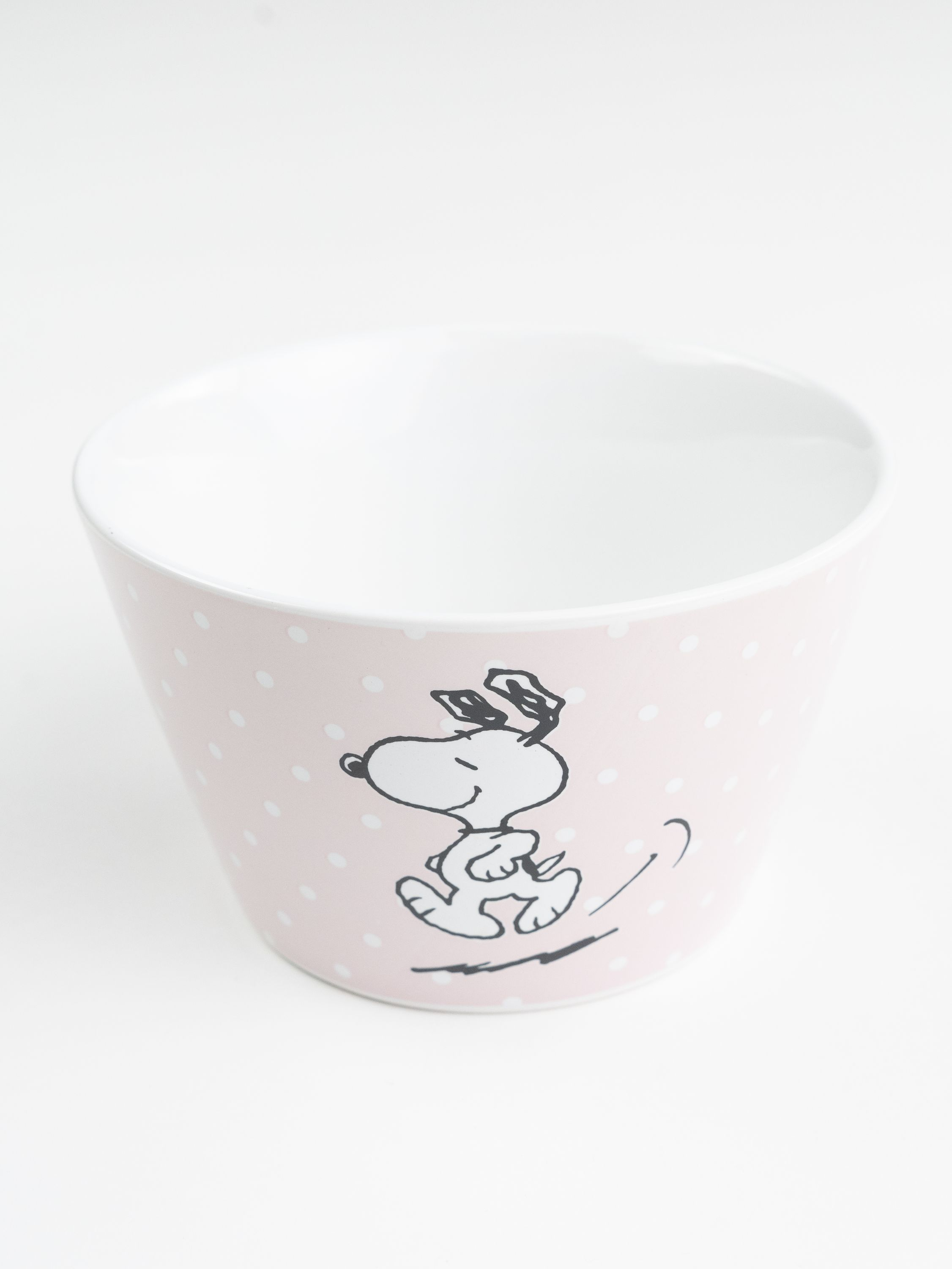 Rosa Snoopy-Becher mit weißen Tupfen und laufendem Snoopy. Weißer Hintergrund.