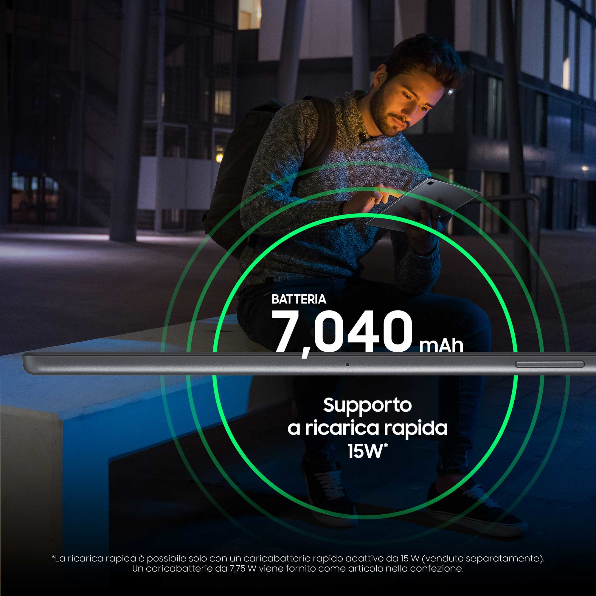 Een man die 's nachts een tablet gebruikt. Een batterijgrafiek met 7.040 mAh wordt weergegeven.