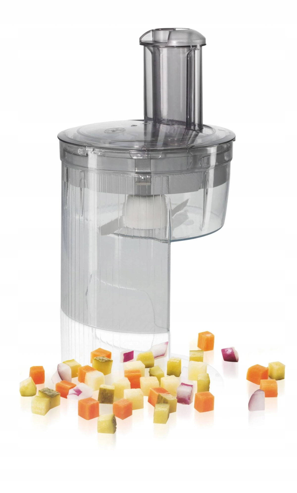 Ein Foodprocessor mit gewürfeltem Gemüse, das auf einer weißen Oberfläche verstreut ist.
