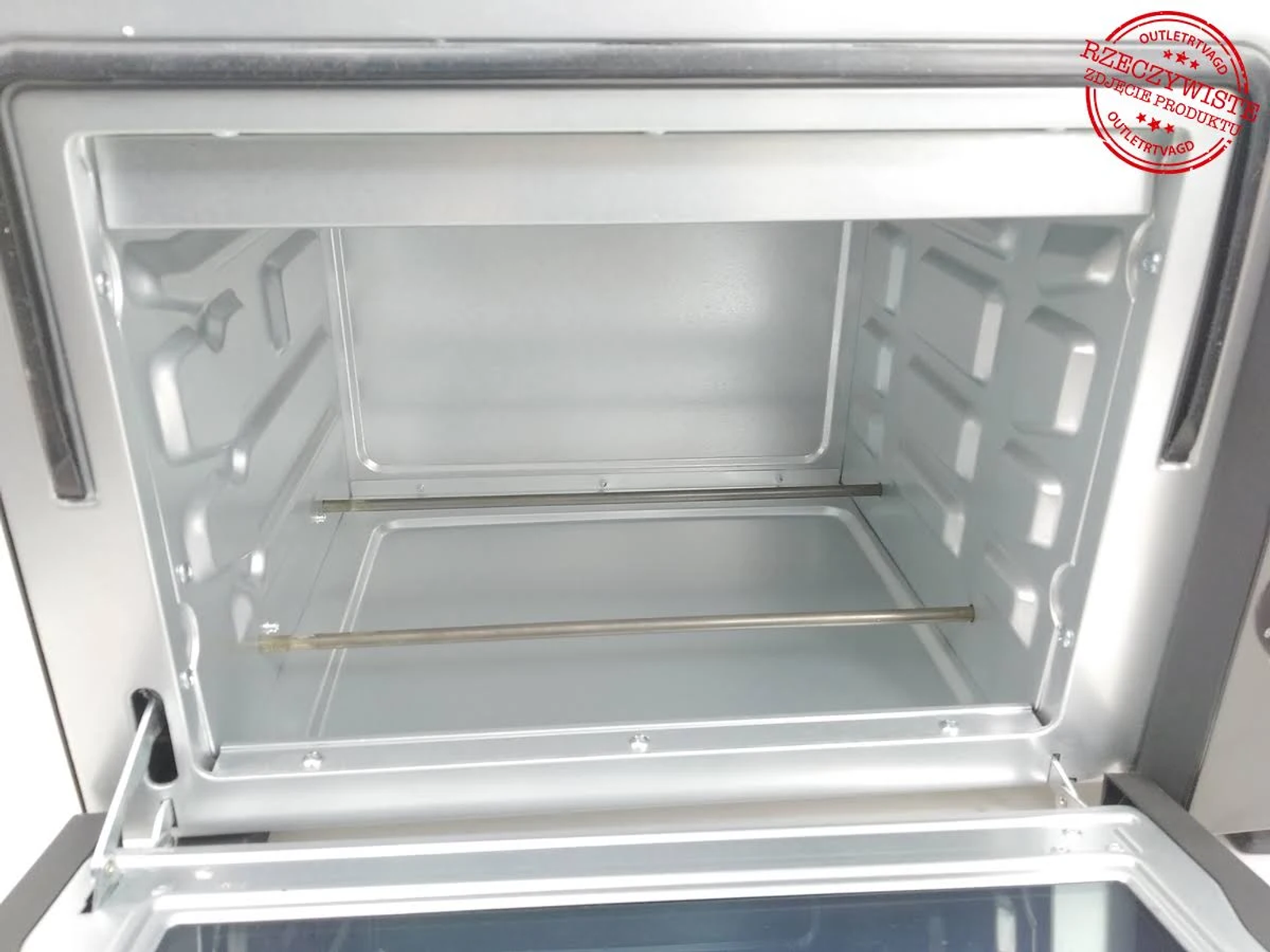 Interior de un horno tostador plateado con rejilla metálica, puerta abierta.