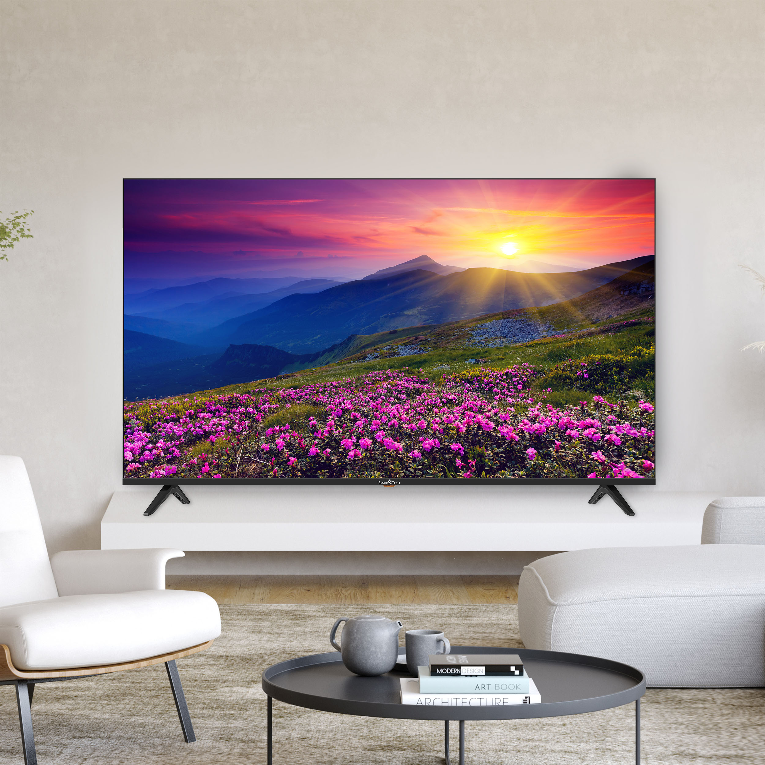 Un televisor grande muestra un atardecer sobre montañas con flores rosas en primer plano. Sillas blancas y una mesa de café al frente.