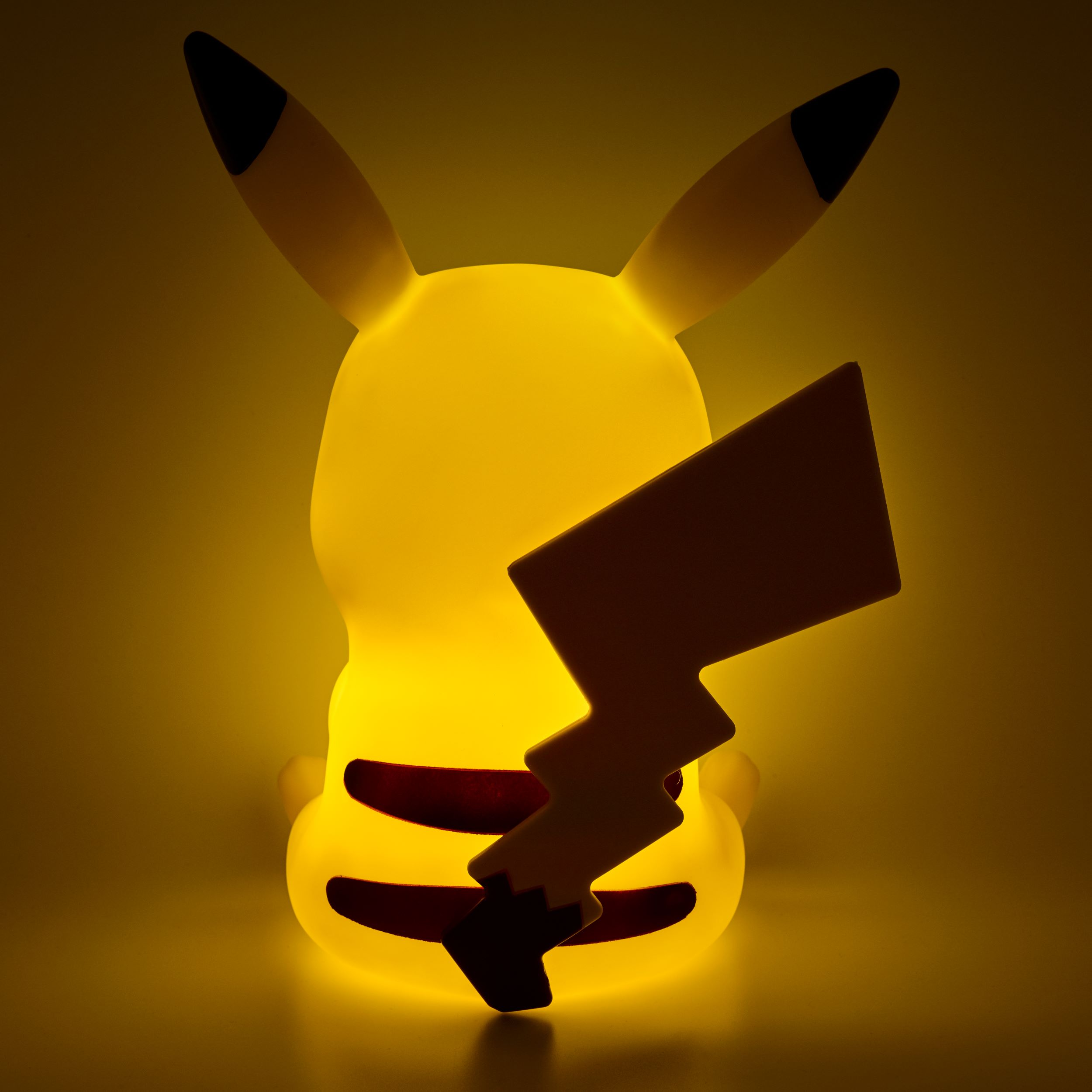 Lampada Pikachu gialla vista da dietro, con ritaglio a forma di fulmine sulla coda. Sfondo giallo.