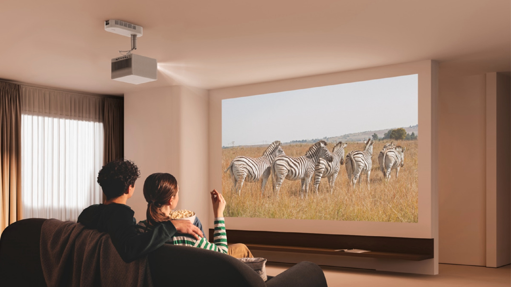 Paar schaut Film auf großem Bildschirm. Zebras sind auf dem Bildschirm. Popcorn ist im Vordergrund.