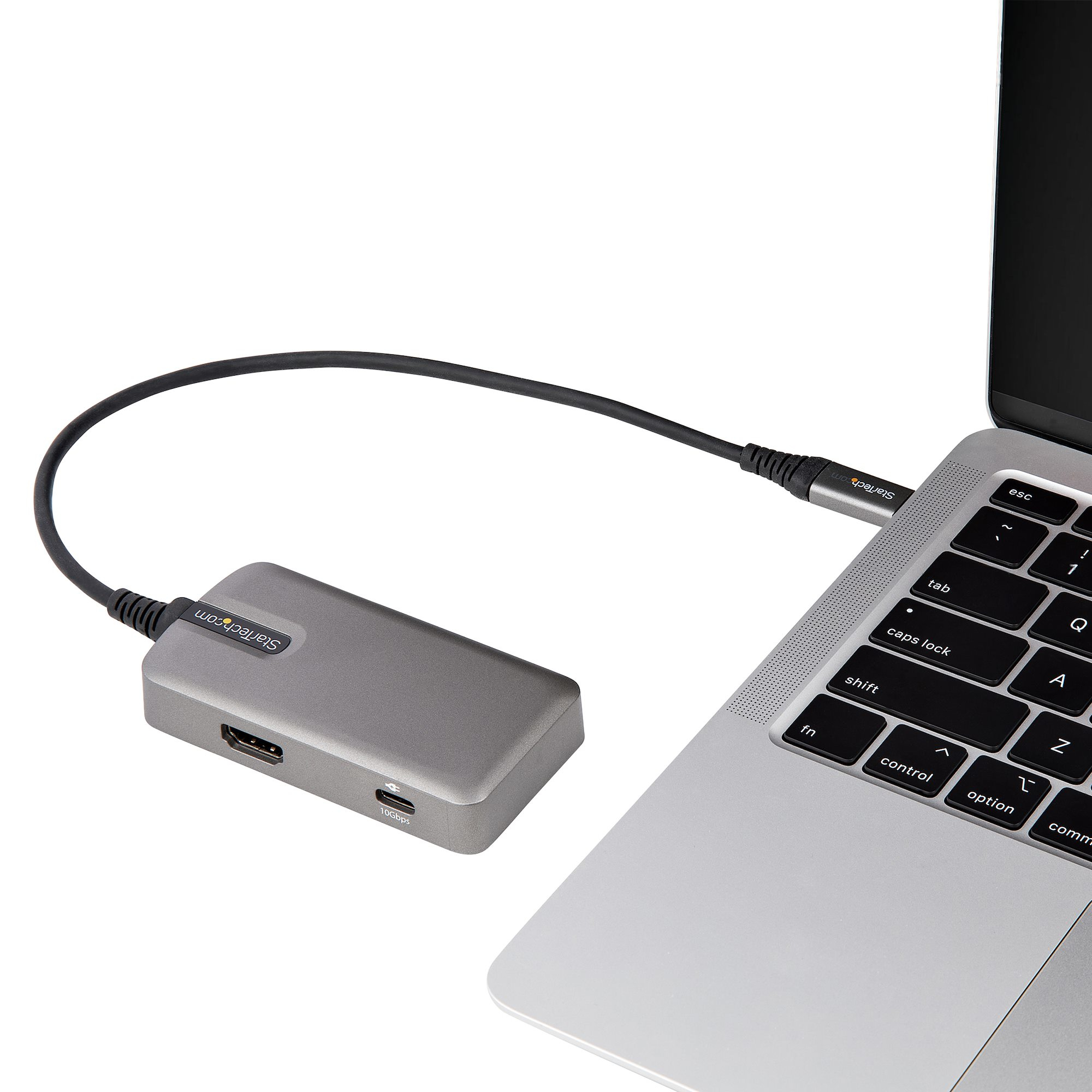 Portátil conectado a un dispositivo Startech gris mediante cable sobre fondo blanco.