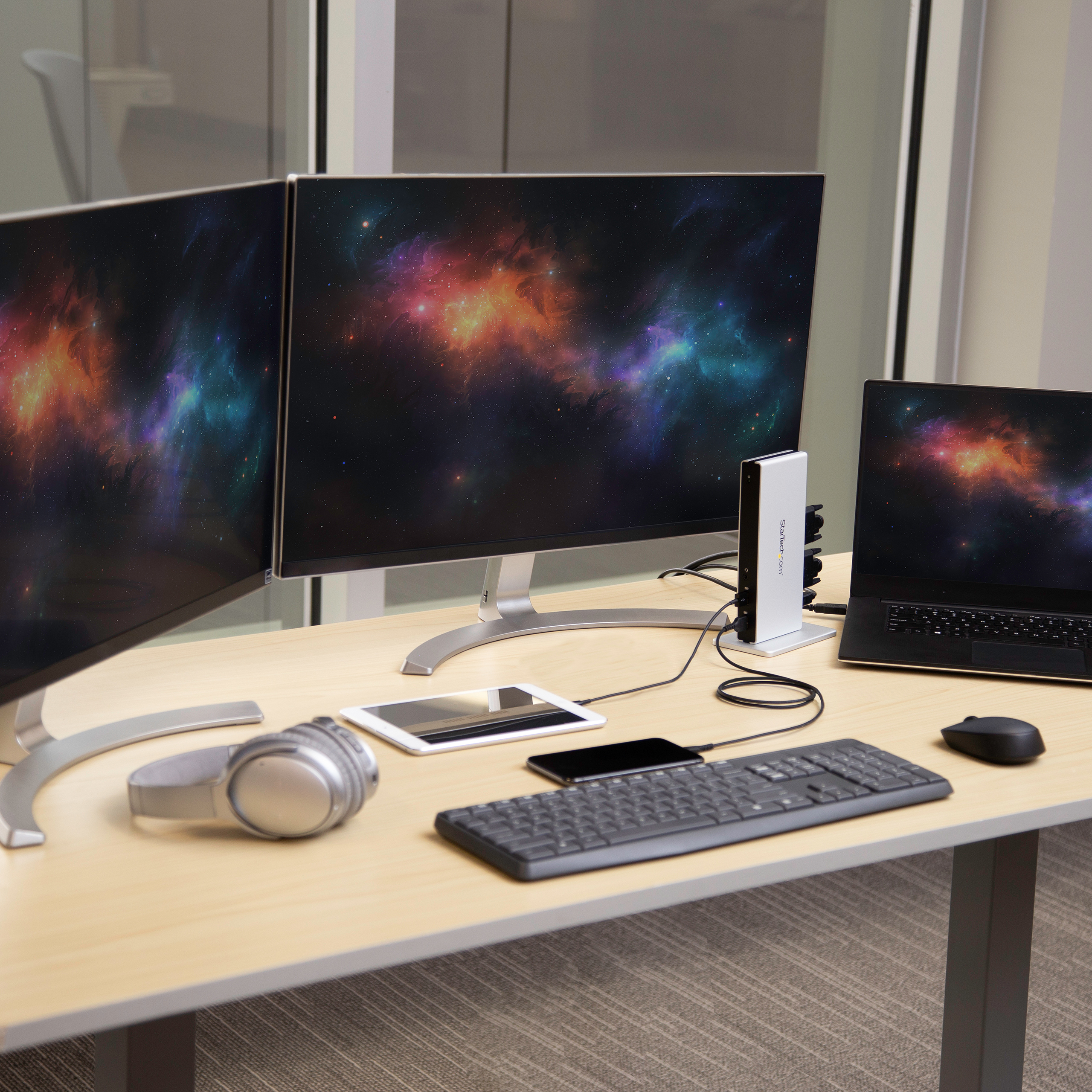 Un'impostazione da scrivania con due monitor, un laptop e periferiche. Un dock li collega.