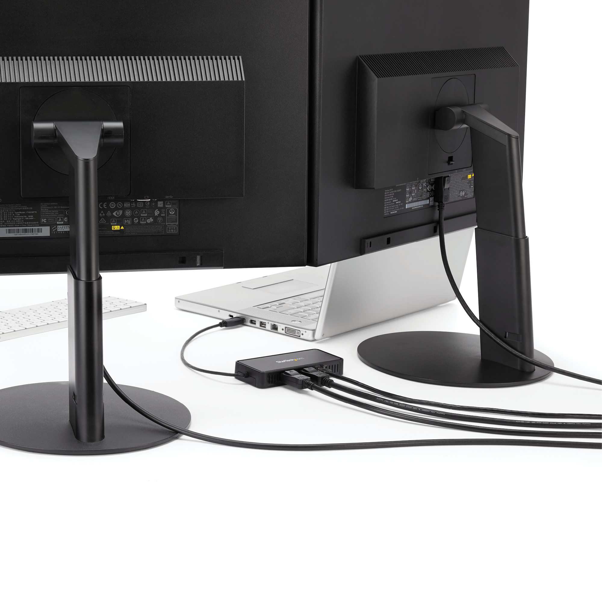 Due monitor neri, un laptop e un hub nero con cavi.