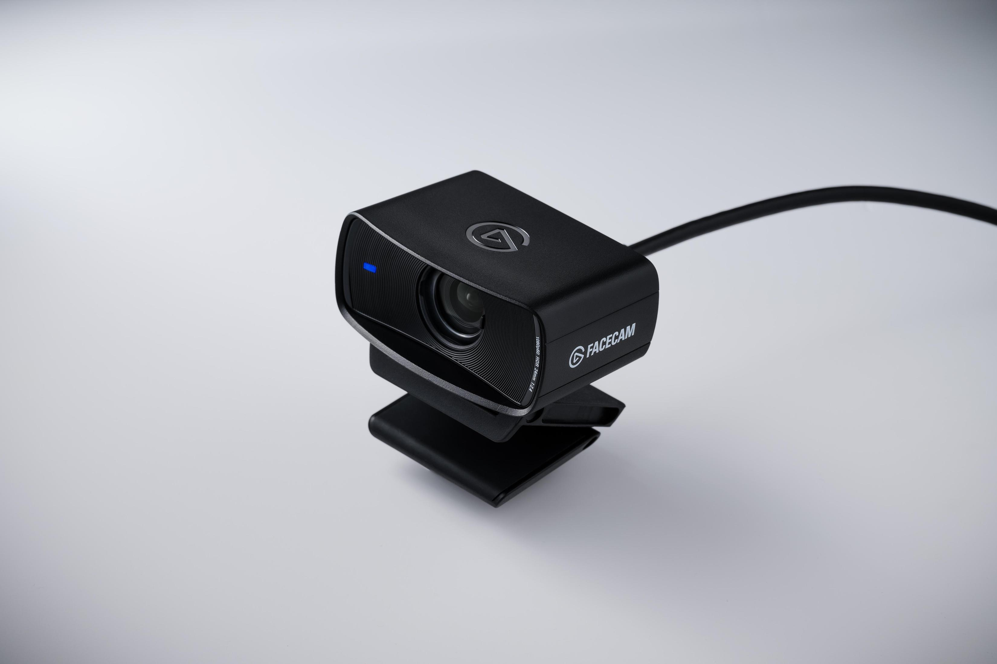 Una webcam nera con luce blu, montata su una superficie bianca.