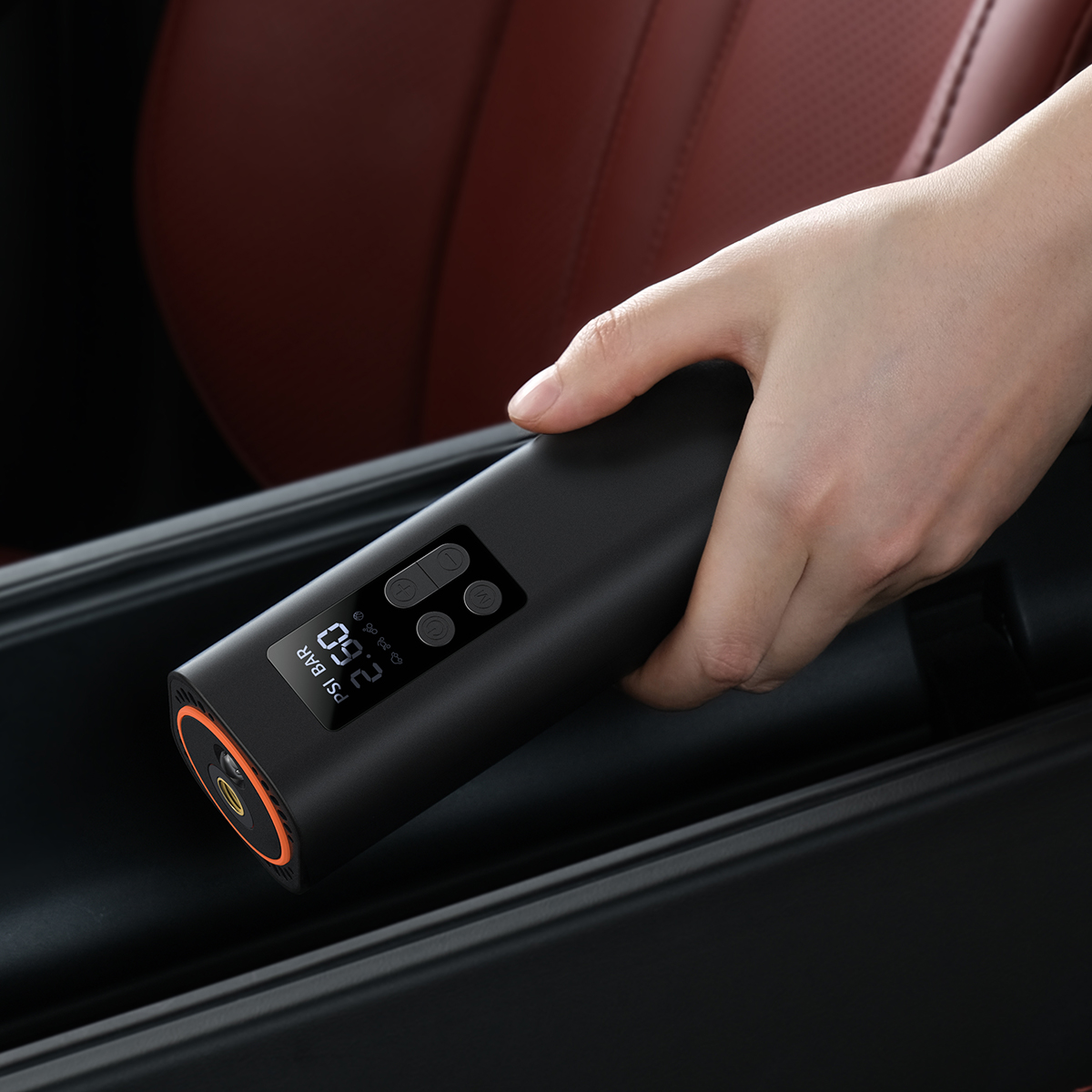 Ręka trzymająca czarną pompkę do powietrza. Wyświetlacz pokazuje ciśnienie w PSI i Bar.