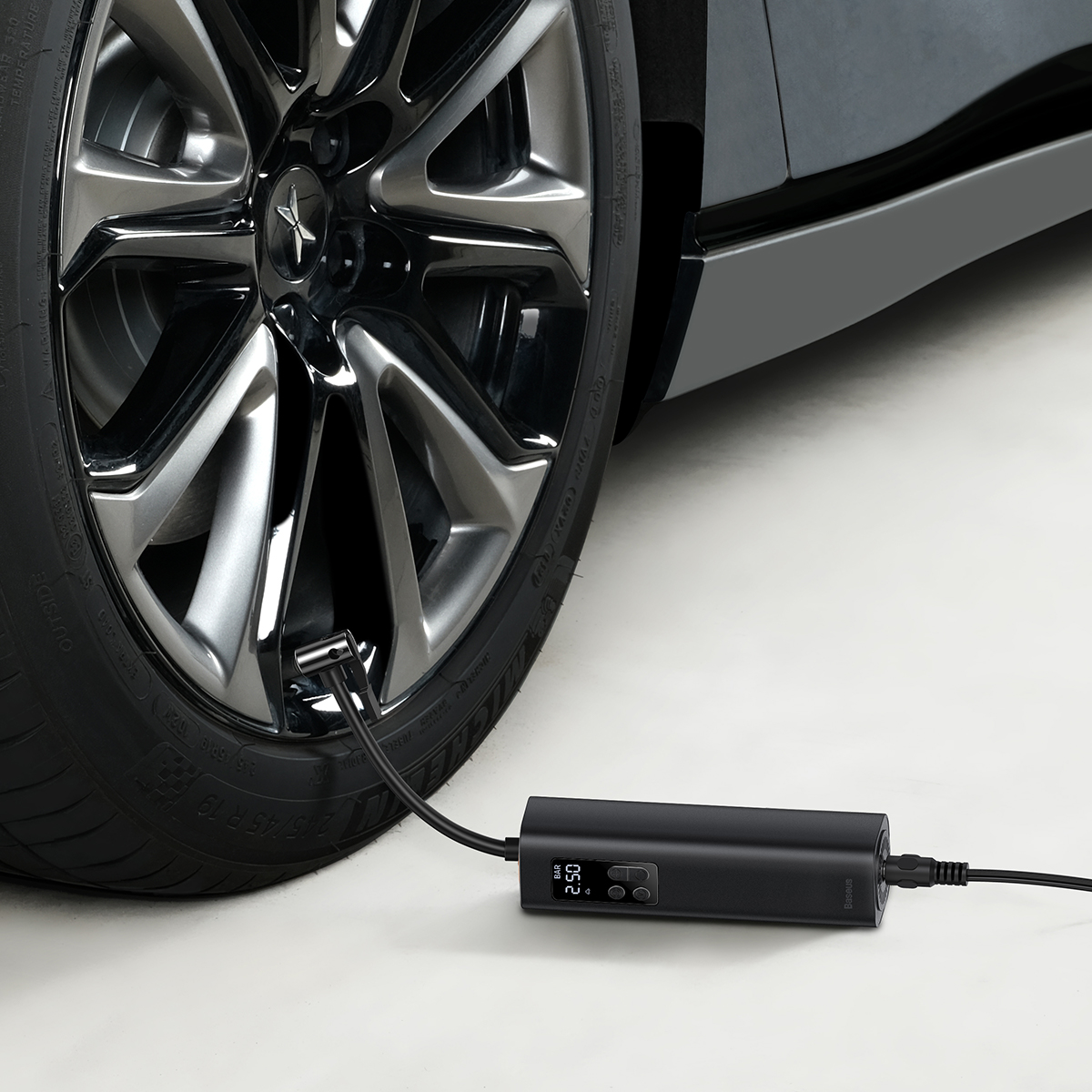 Czarna opona pompowana przez czarną przenośną pompkę. Pompa wyświetla odczyt ciśnienia.