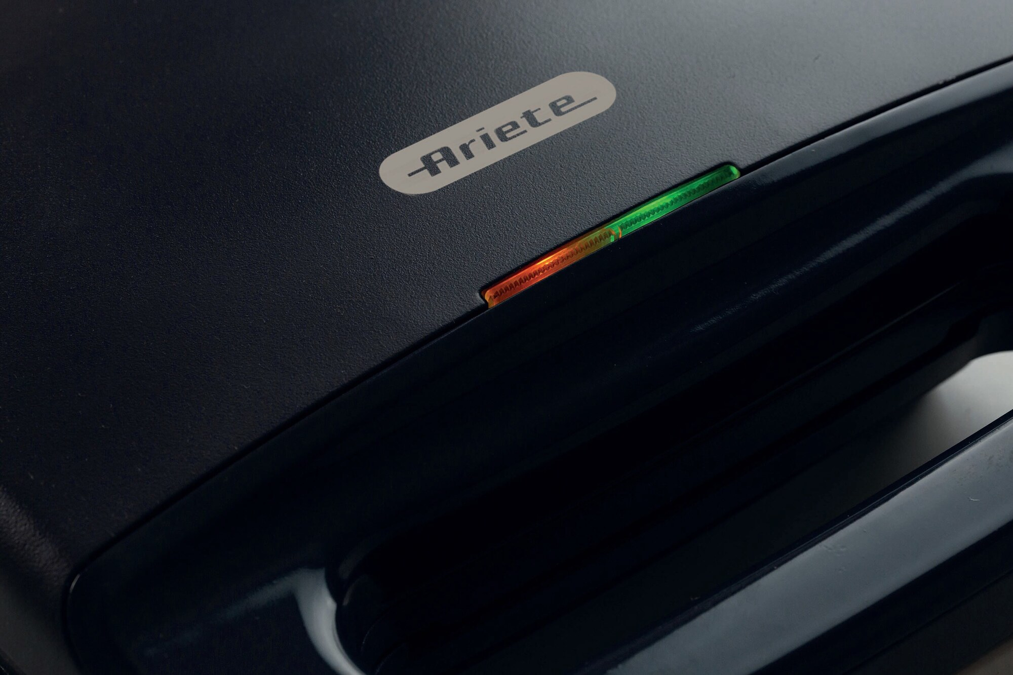 Zbliżenie na ciemnoniebieską gofrownicę Ariete z czerwonymi i zielonymi lampkami kontrolnymi.
