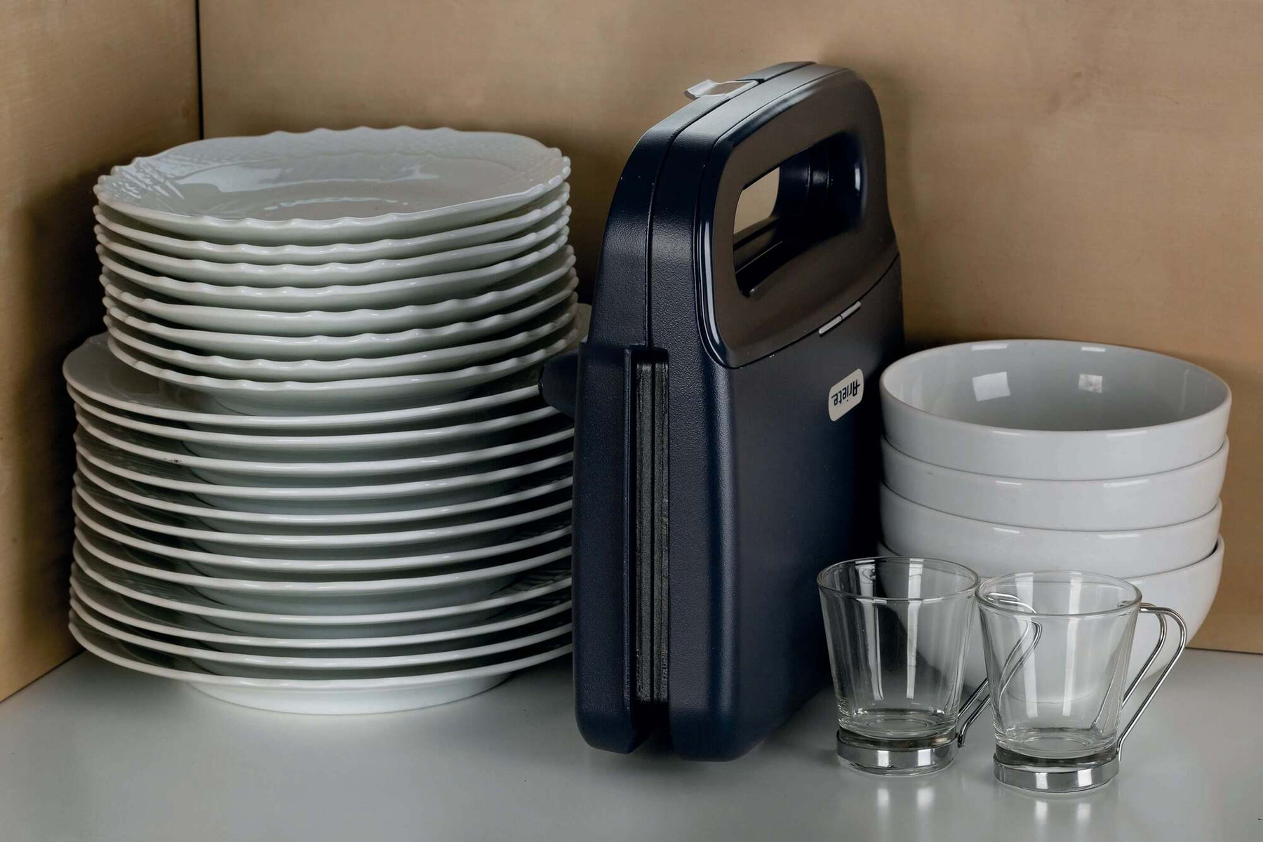 Blat kuchenny z talerzami, miskami, opiekaczem do kanapek i szklankami.