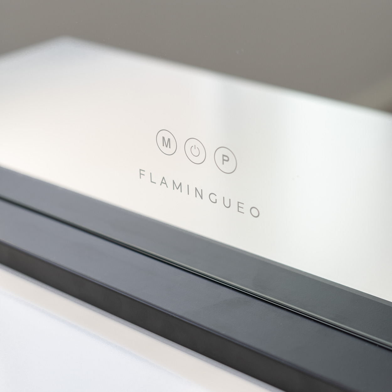 Primer plano de un panel blanco con tres símbolos circulares y la palabra FLAMINGUEO.
