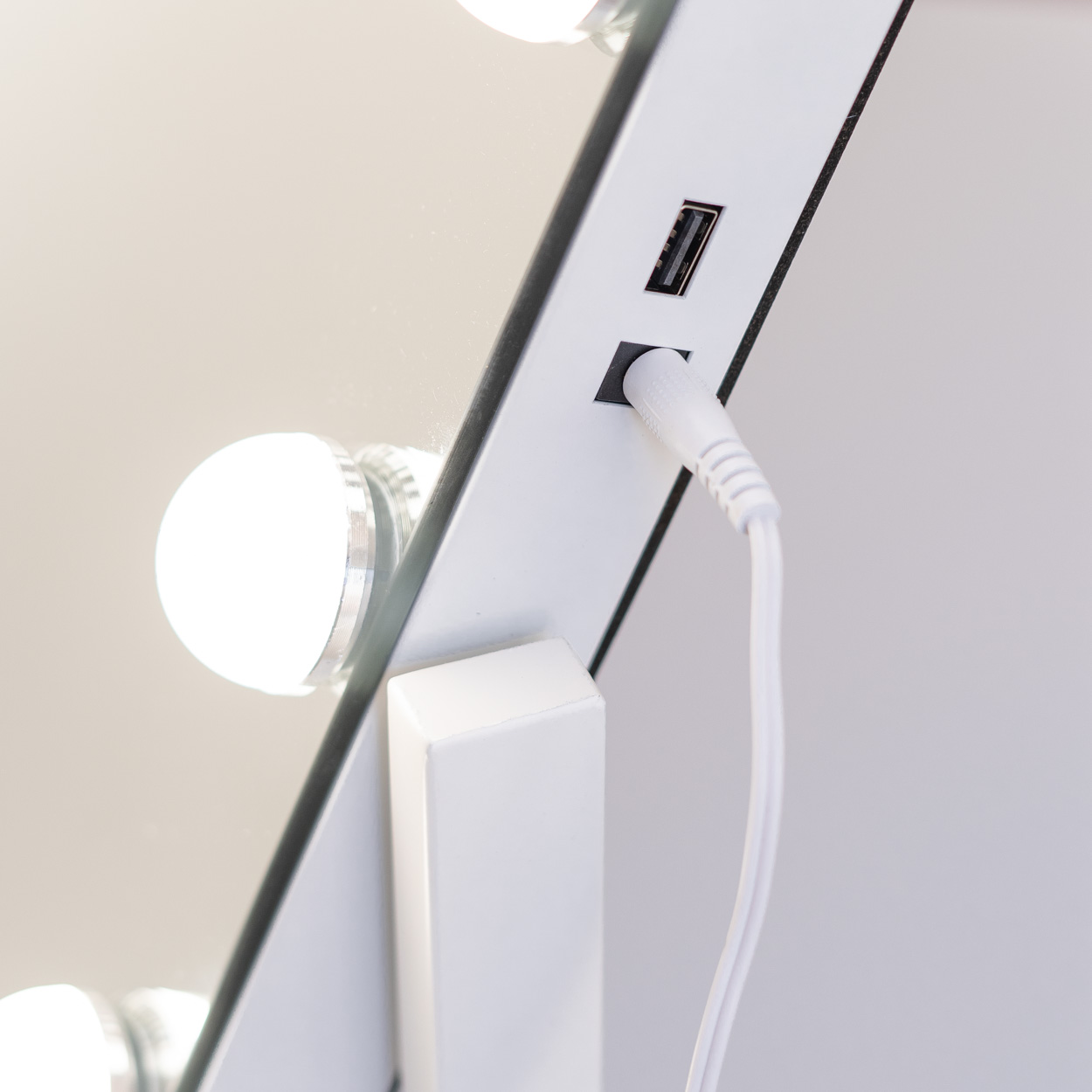Primer plano de un espejo con luces, USB y entradas de corriente. Marco blanco.