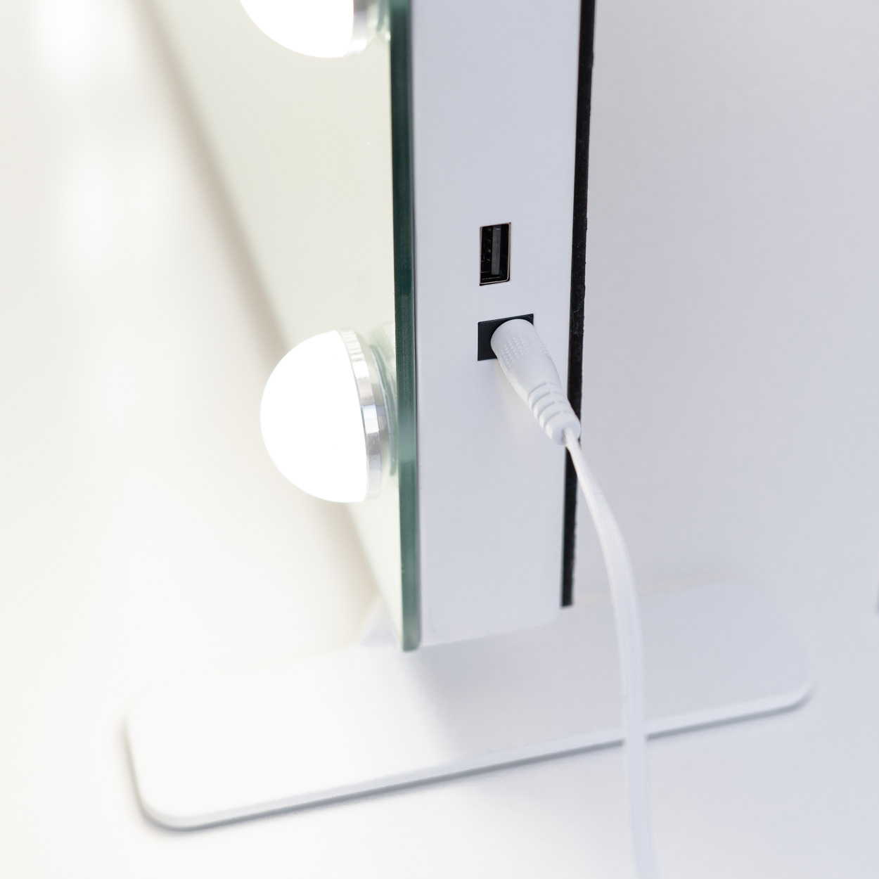 Primer plano de un espejo de maquillaje iluminado con cable de alimentación y puerto USB.