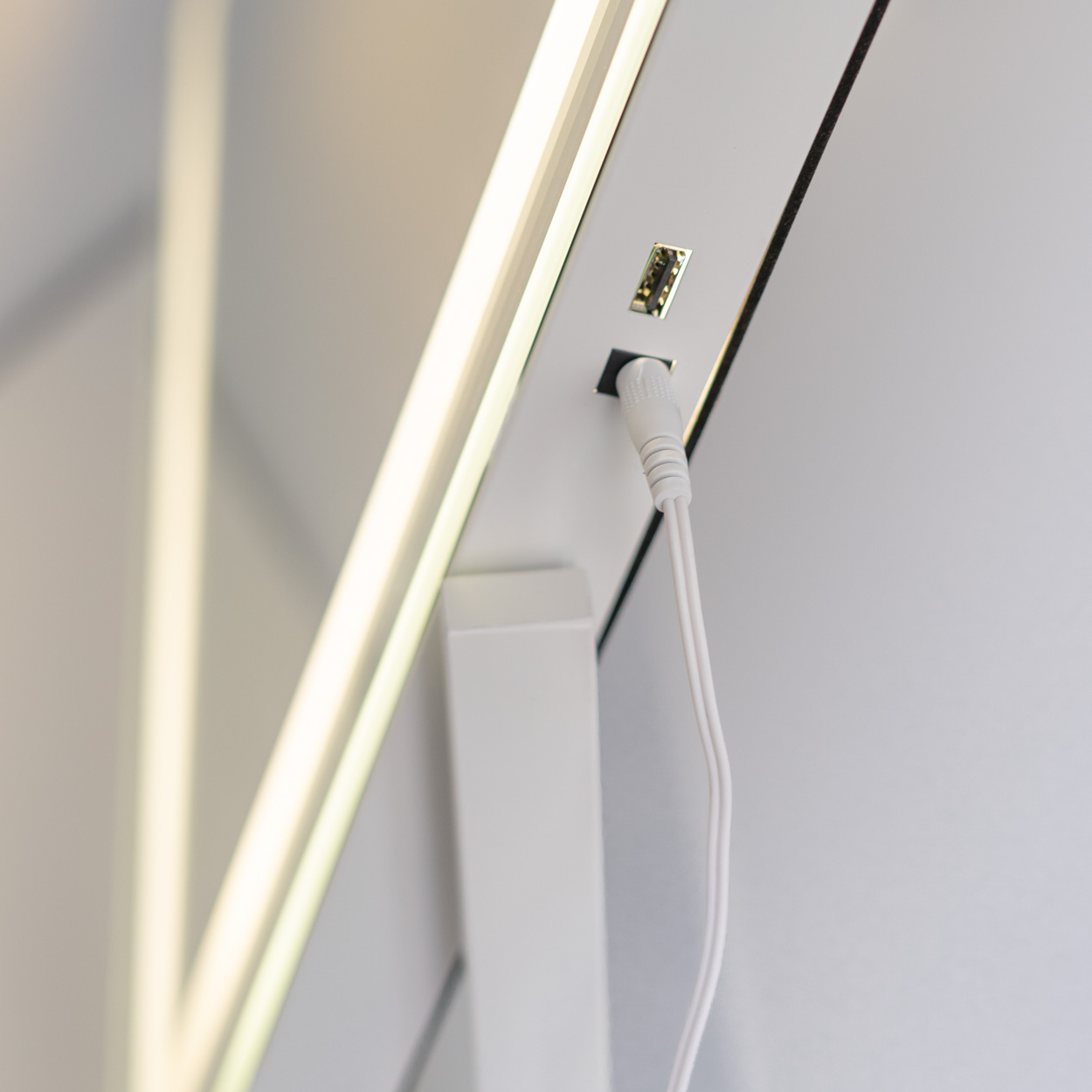 Primer plano de la parte posterior de un espejo con un cable de alimentación y un puerto USB.
