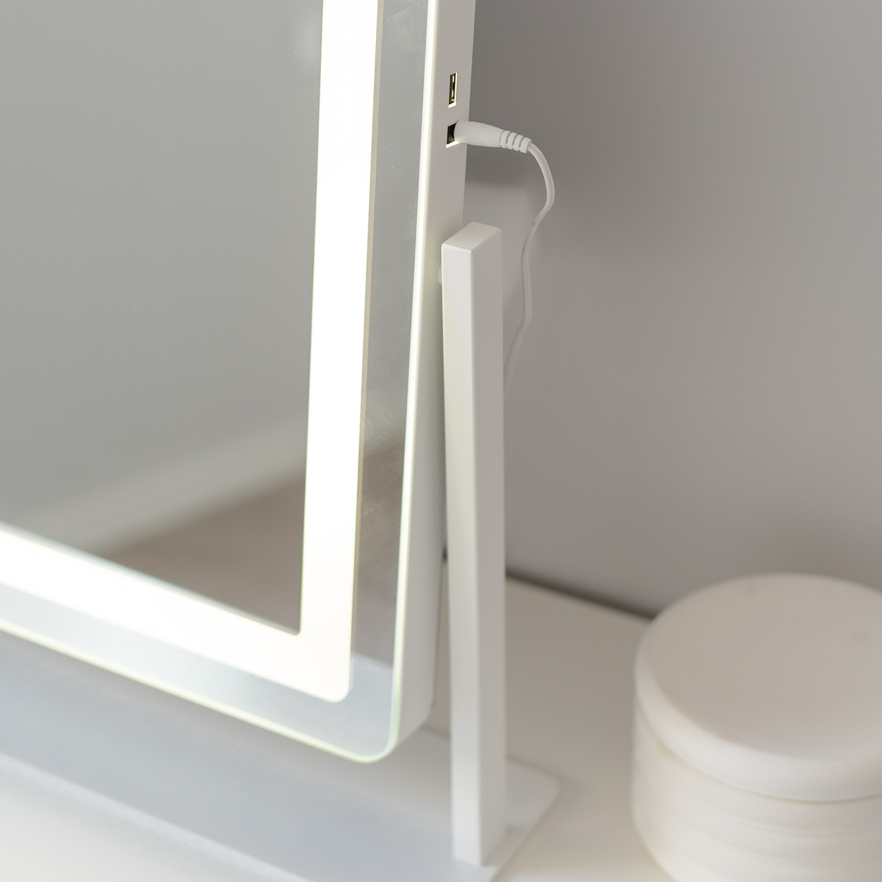 Espejo de tocador blanco moderno con luces LED, un puerto USB y un pequeño recipiente cosmético.