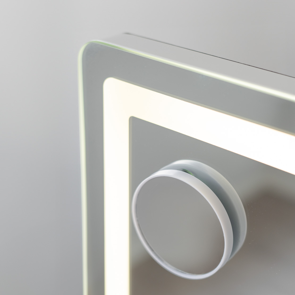 Un espejo iluminado con un pequeño espejo de aumento adjunto en el lateral.