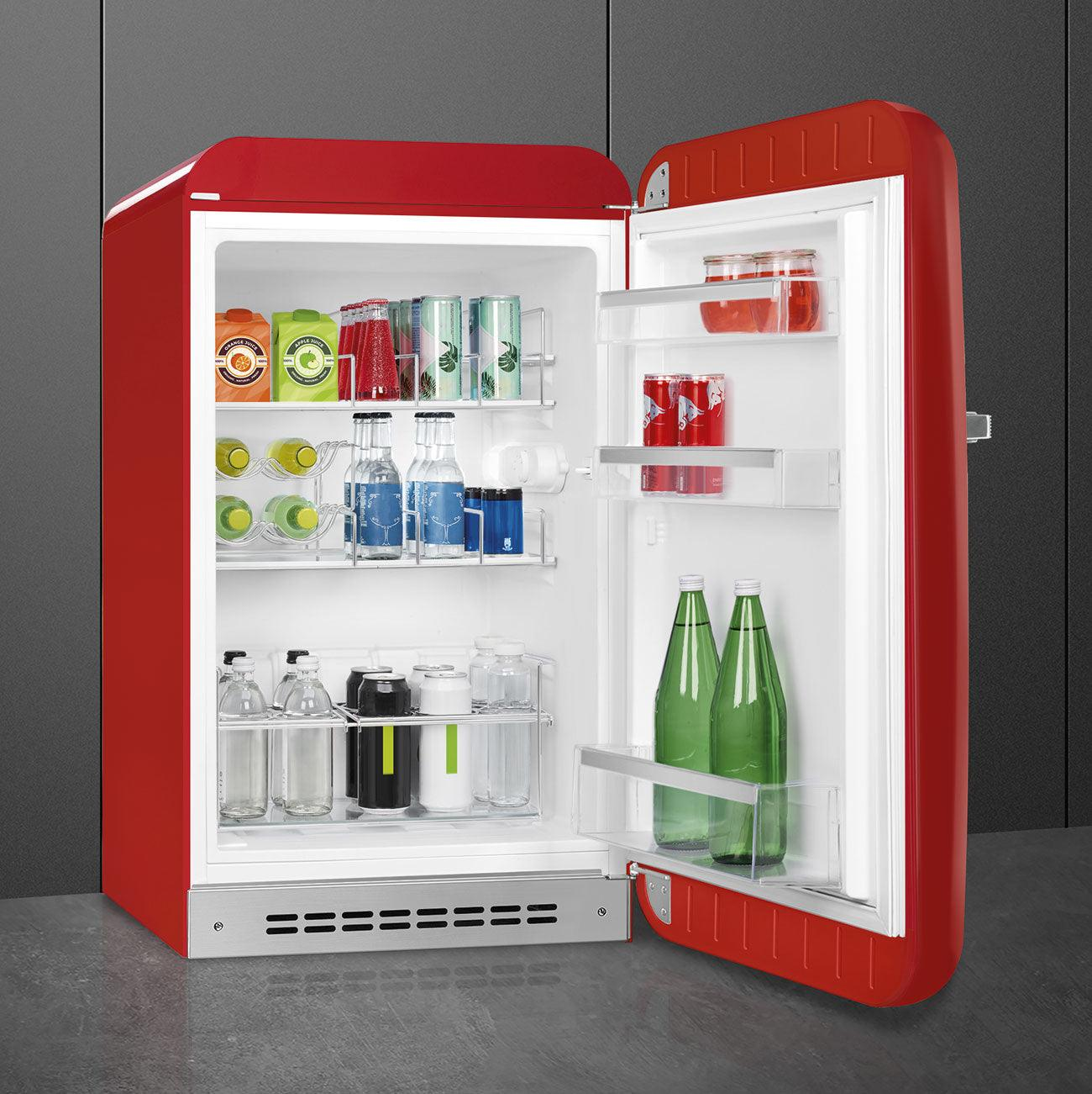 Un mini-refrigerador rojo, abierto, revelando bebidas y botellas en estantes.
