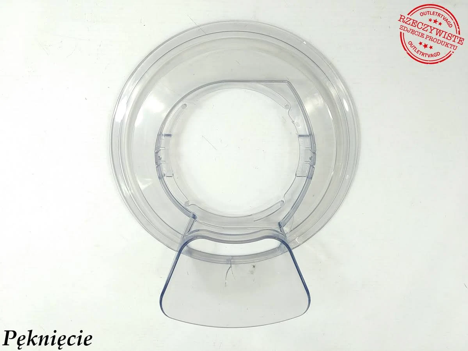 Ein transparenter Kunststoffdeckel mit Griff, Draufsicht, zeigt einen Riss.