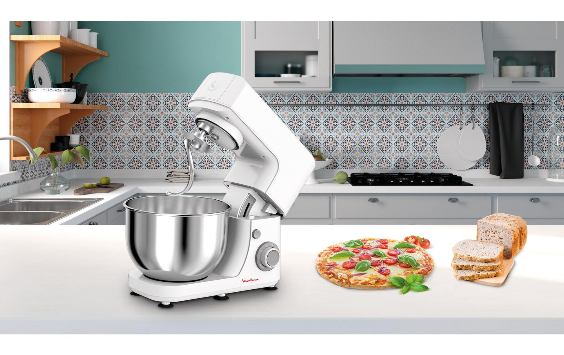 Robot da cucina bianco, pizza con pomodori e basilico e pane su un bancone bianco.