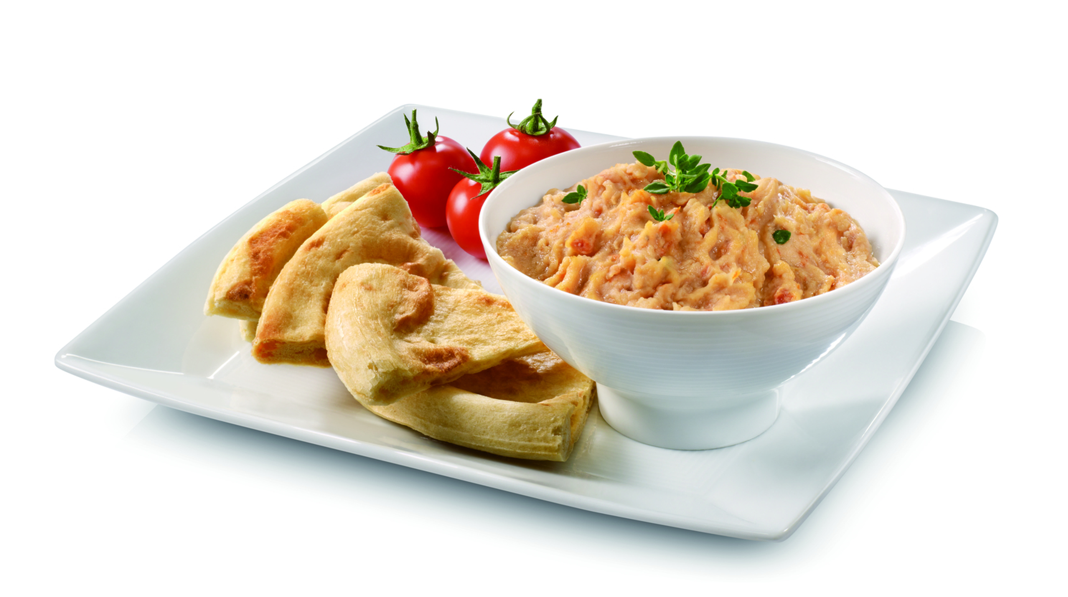 Weiße Schüssel mit Dip, Fladenbrot und Tomaten auf weißem Teller. Isoliert weißer Hintergrund.