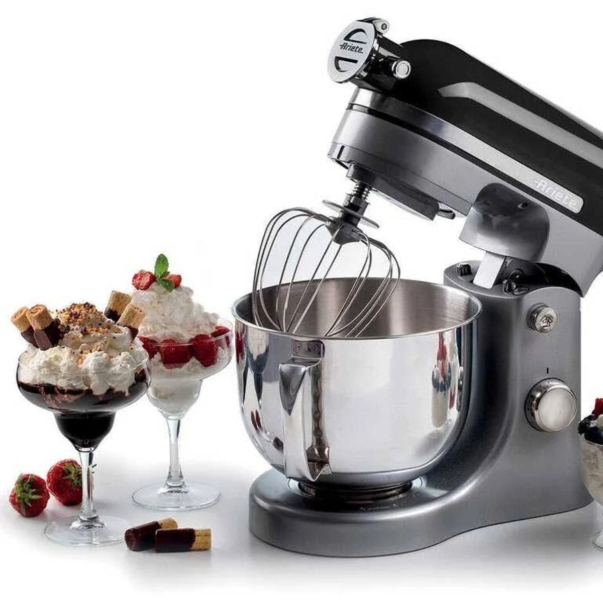 Silberfarbener Ariete-Küchenmixer mit Schüssel und Aufsätzen. Desserts links. Weißer Hintergrund.