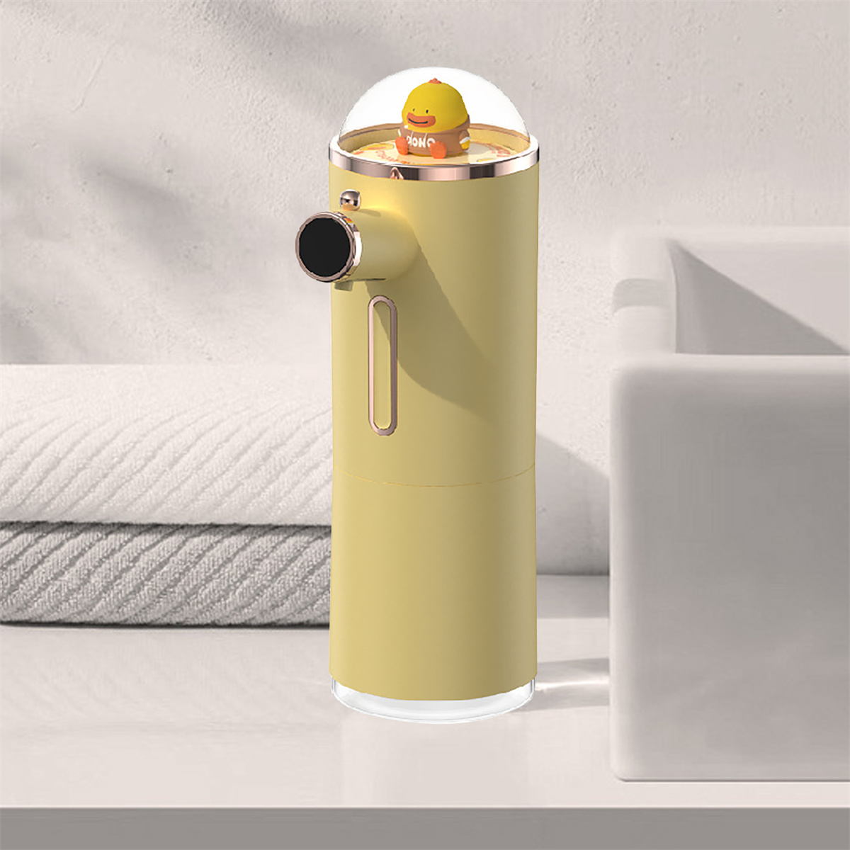 Ein gelber automatischer Seifenspender mit einer Cartoon-Ente oben, auf weißer Oberfläche.