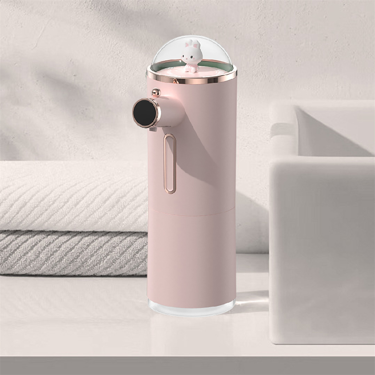 Ein rosa automatischer Seifenspender mit einem kleinen Bären obenauf, vor weißem Hintergrund.