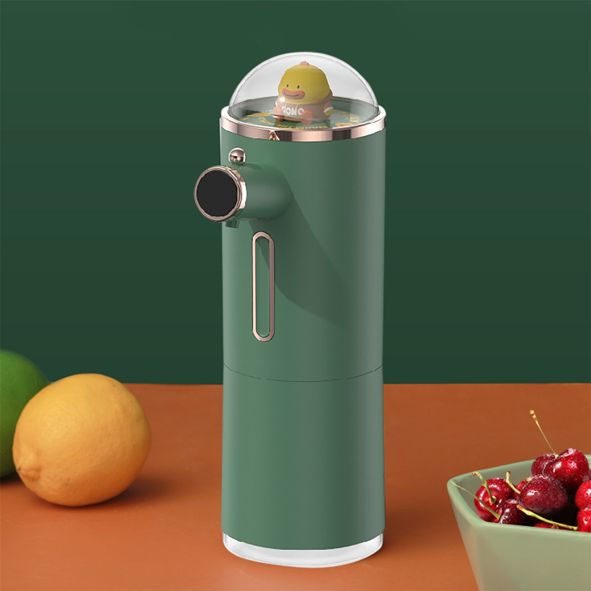 Grüner automatischer Seifenspender mit Entenfigur und klarer Kuppel. Zitronen und Kirschen sind sichtbar.