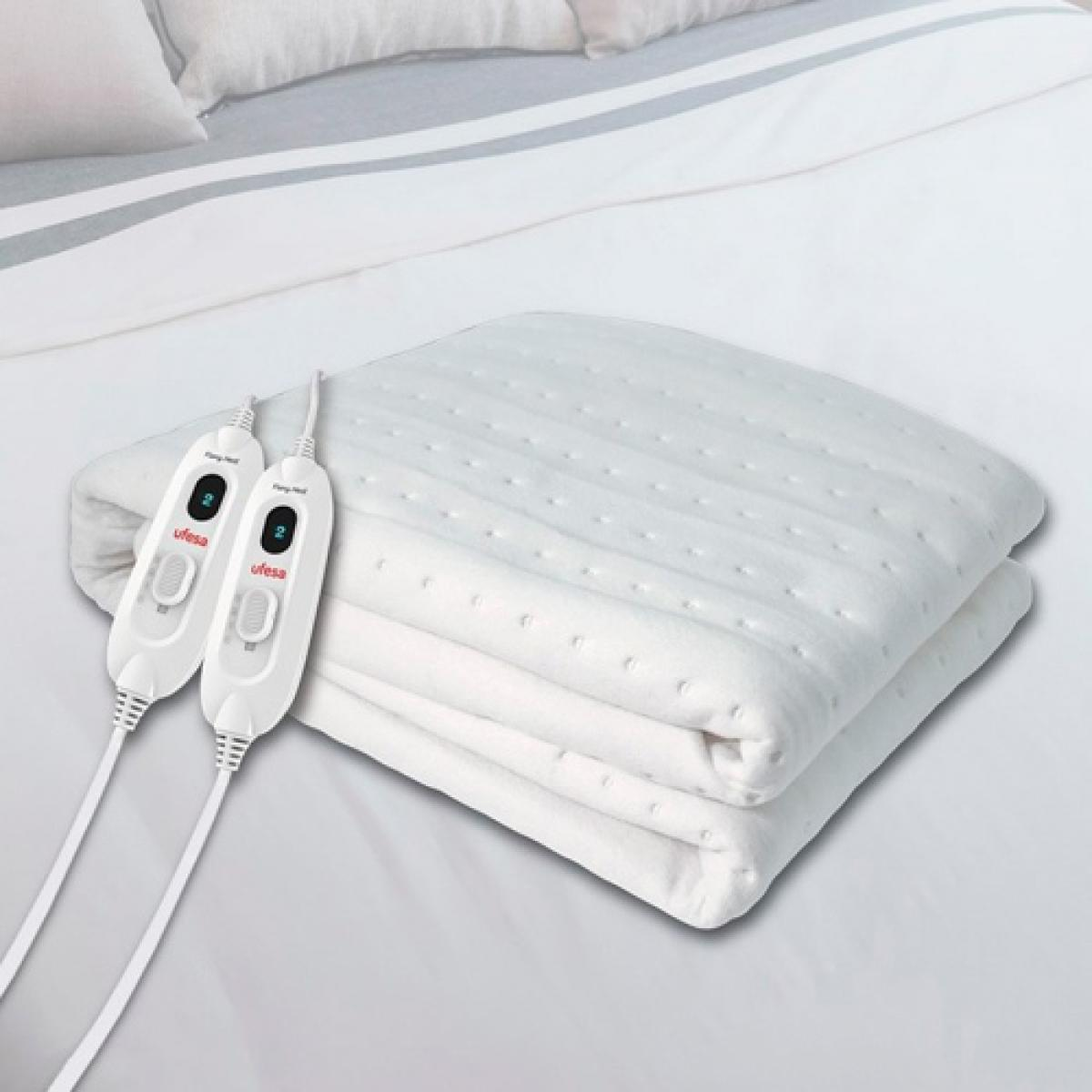 Złożony, biały koc elektryczny z kontrolerami na łóżku.