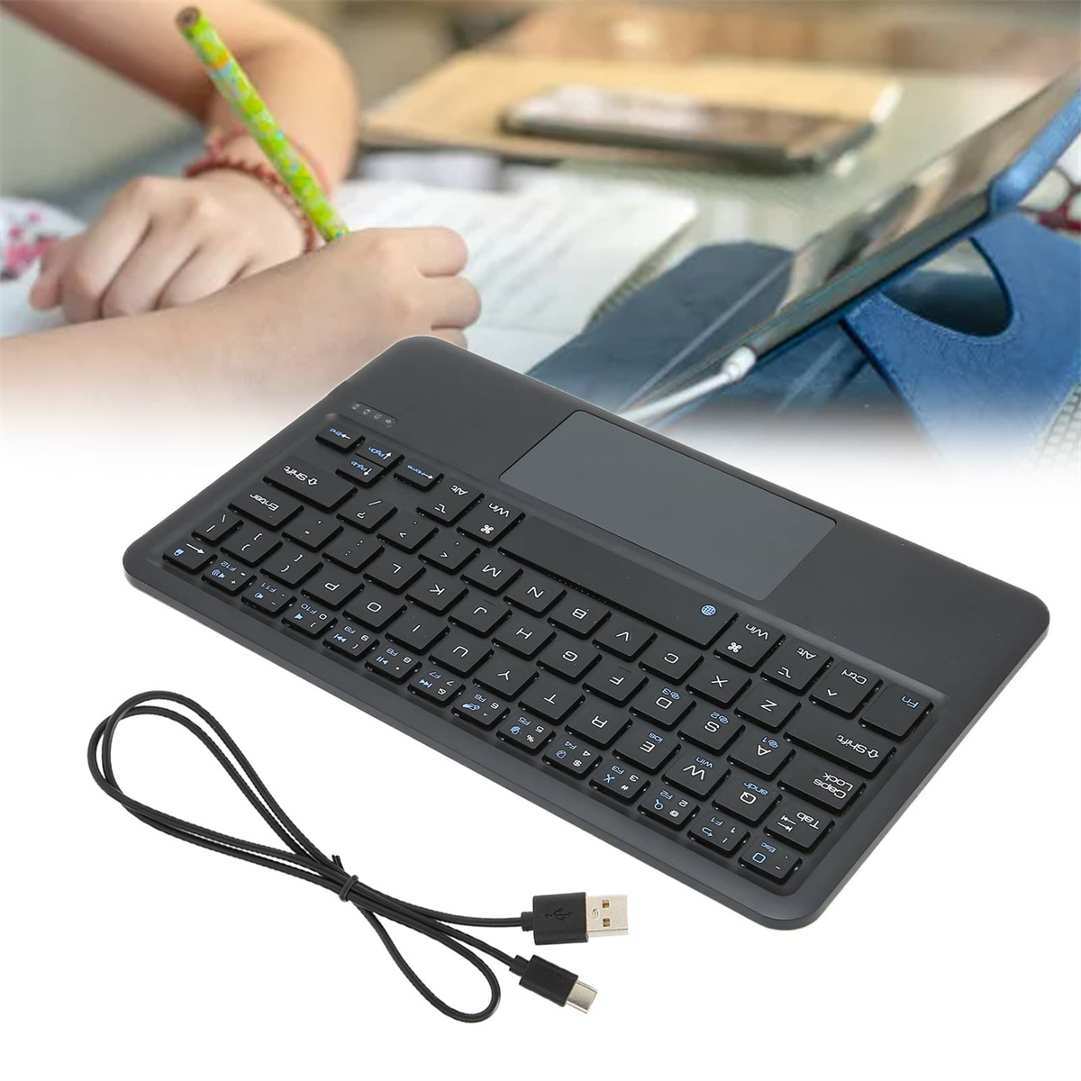 Eine schwarze Tastatur und ein Touchpad liegen auf einem Tisch. Unten befindet sich ein USB-Kabel.