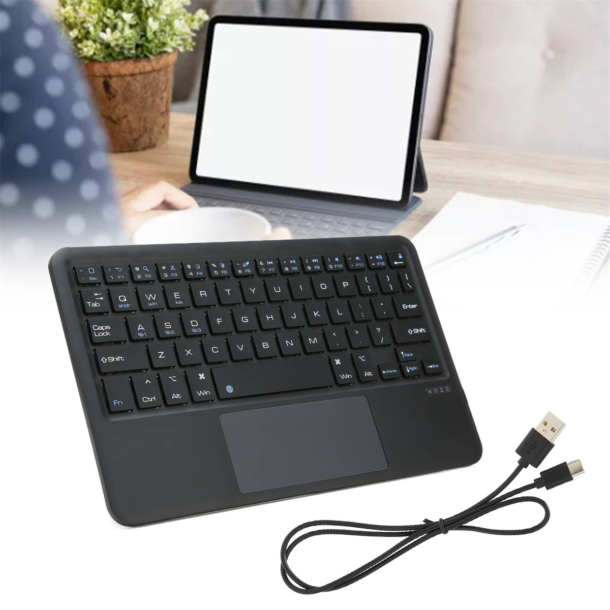 Schwarze Tastatur mit Touchpad und Ladekabel.