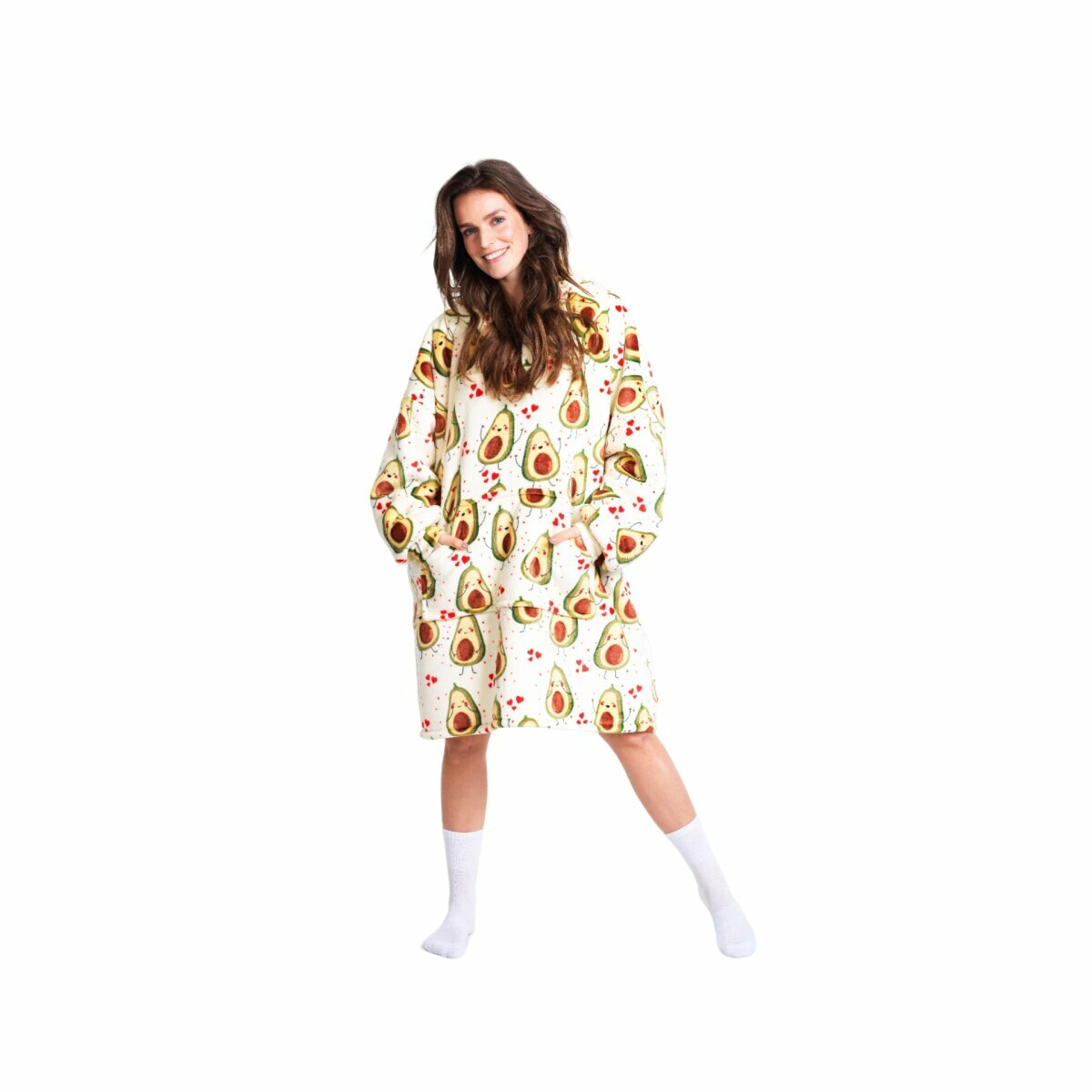 Frau in Schlafanzug mit Avocadomuster lächelt, Hände in Taschen, weißer Hintergrund.
