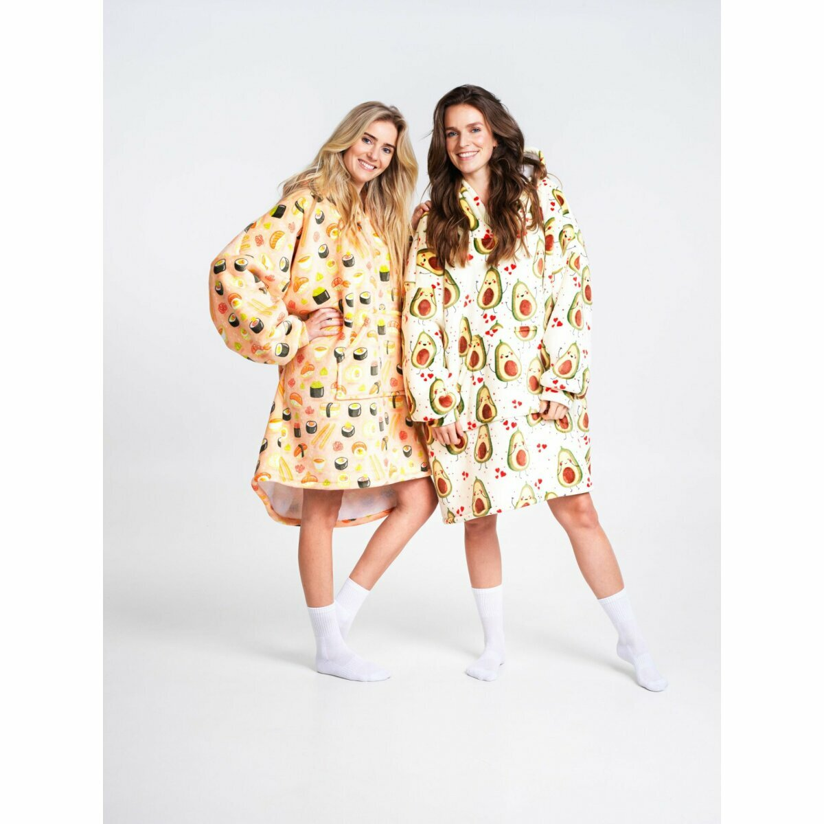 Zwei Frauen tragen übergroße Kapuzenpullover mit Sushi- und Avocado-Muster und stehen zusammen.