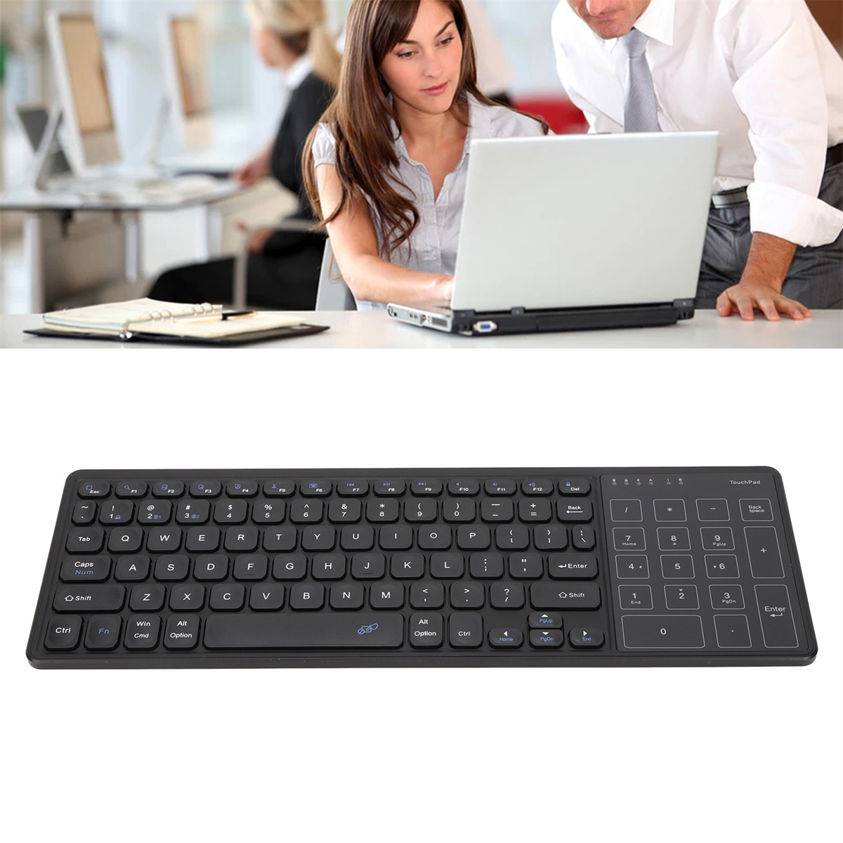Schwarze Tastatur mit Touchpad, Personen arbeiten im Hintergrund.