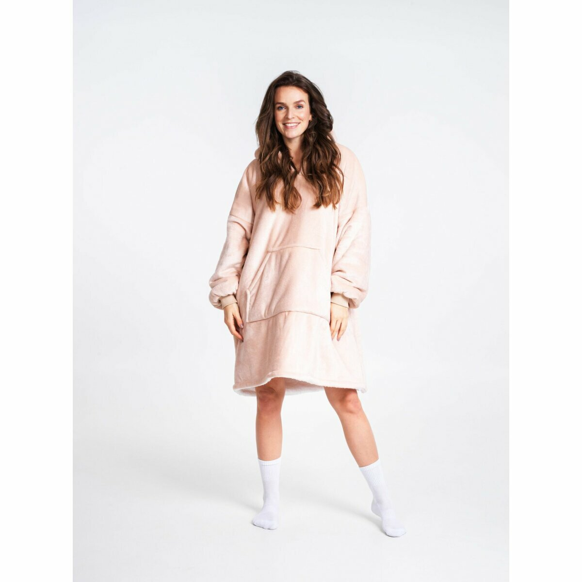 Frau in einem rosa übergroßen Kapuzenpullover und weißen Socken vor weißem Hintergrund.