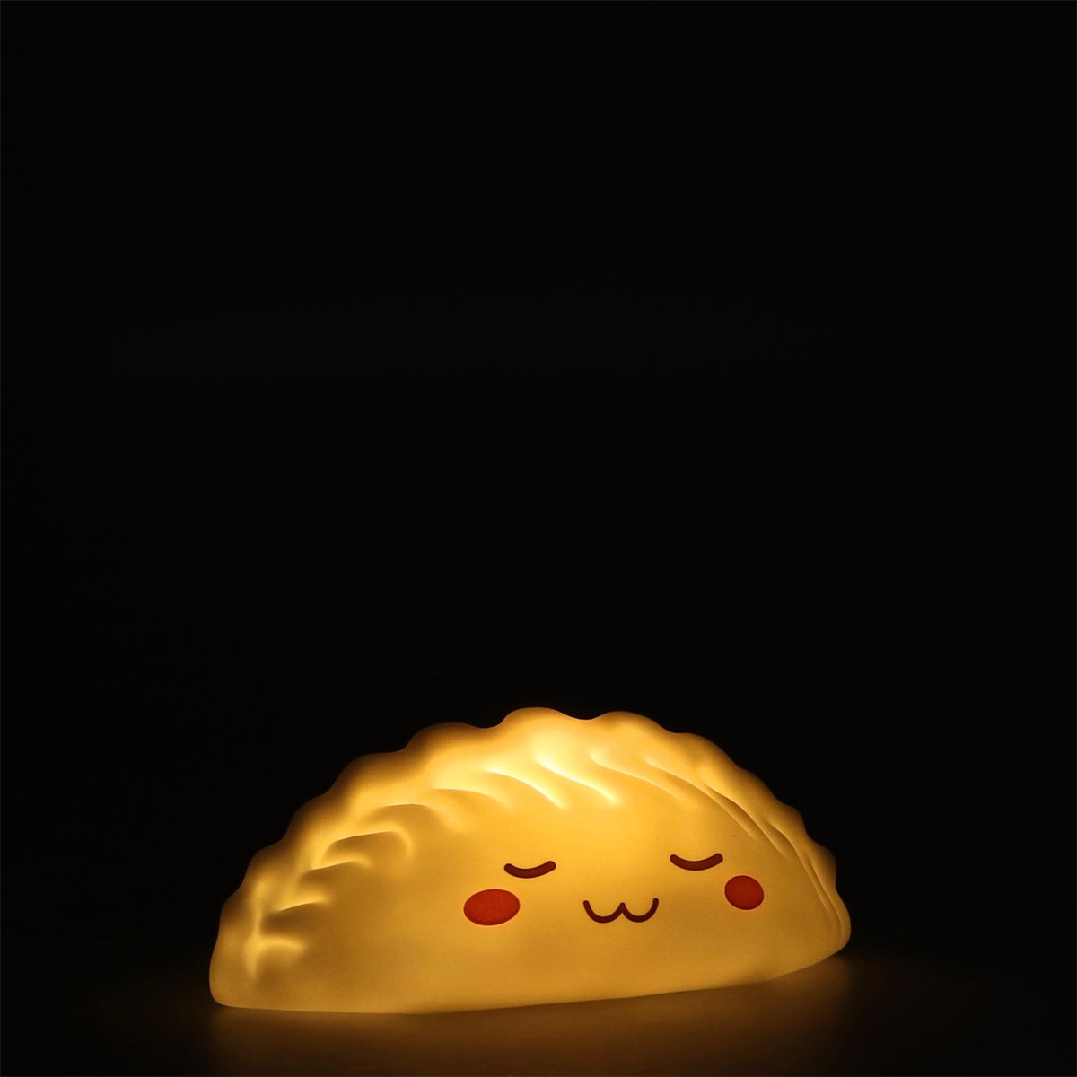 Eine knödelartige Lampe mit einem glücklichen Gesicht auf schwarzem Hintergrund.