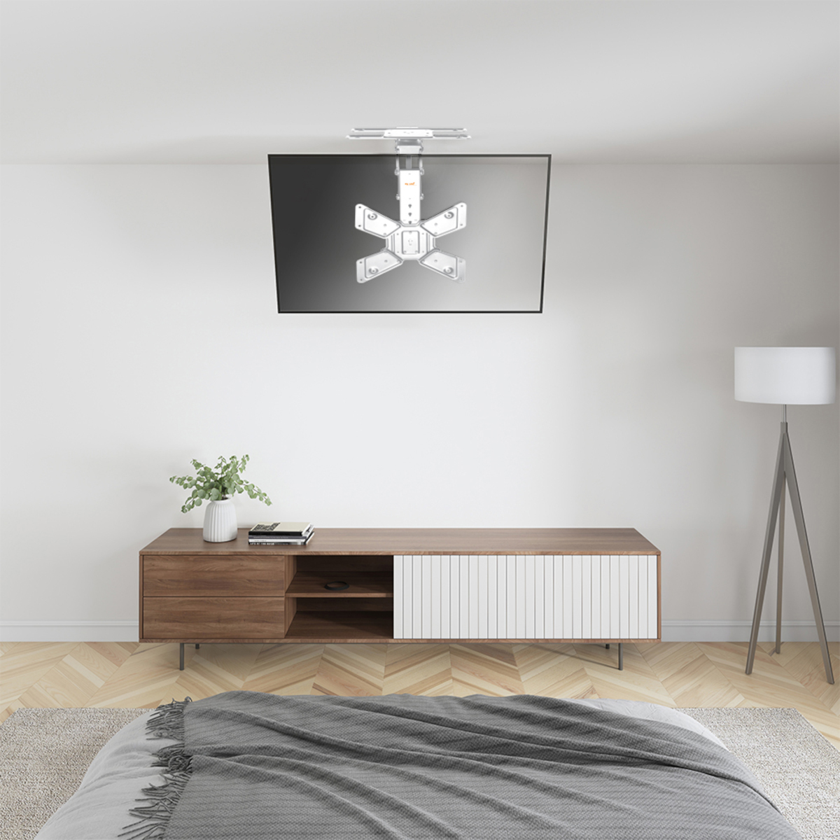TV montata a soffitto, sopra un mobile in legno. Stanza con pareti bianche e un letto grigio.