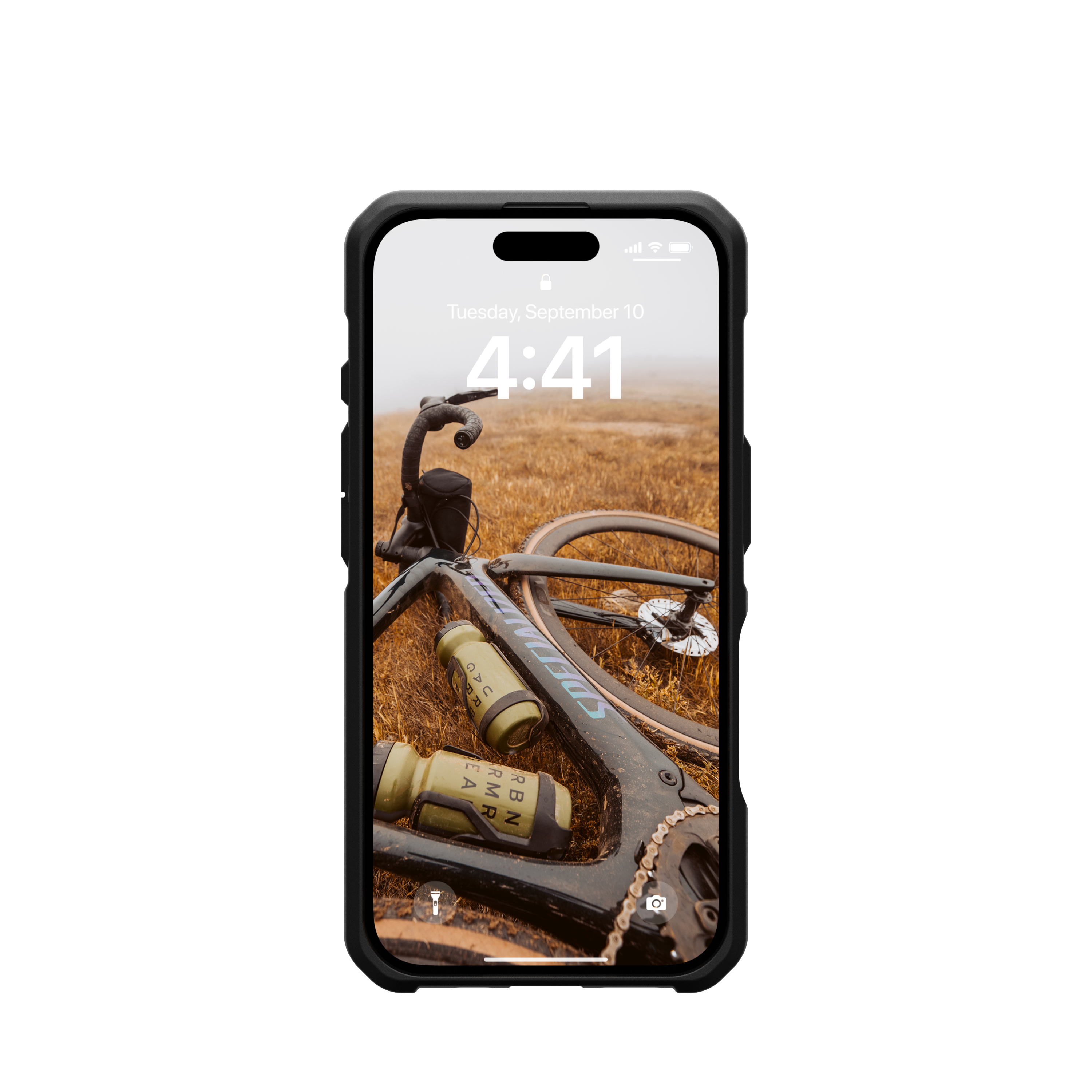 Smartphone con immagine di bici come sfondo. Il telefono è in una custodia nera, appoggiato su un campo.