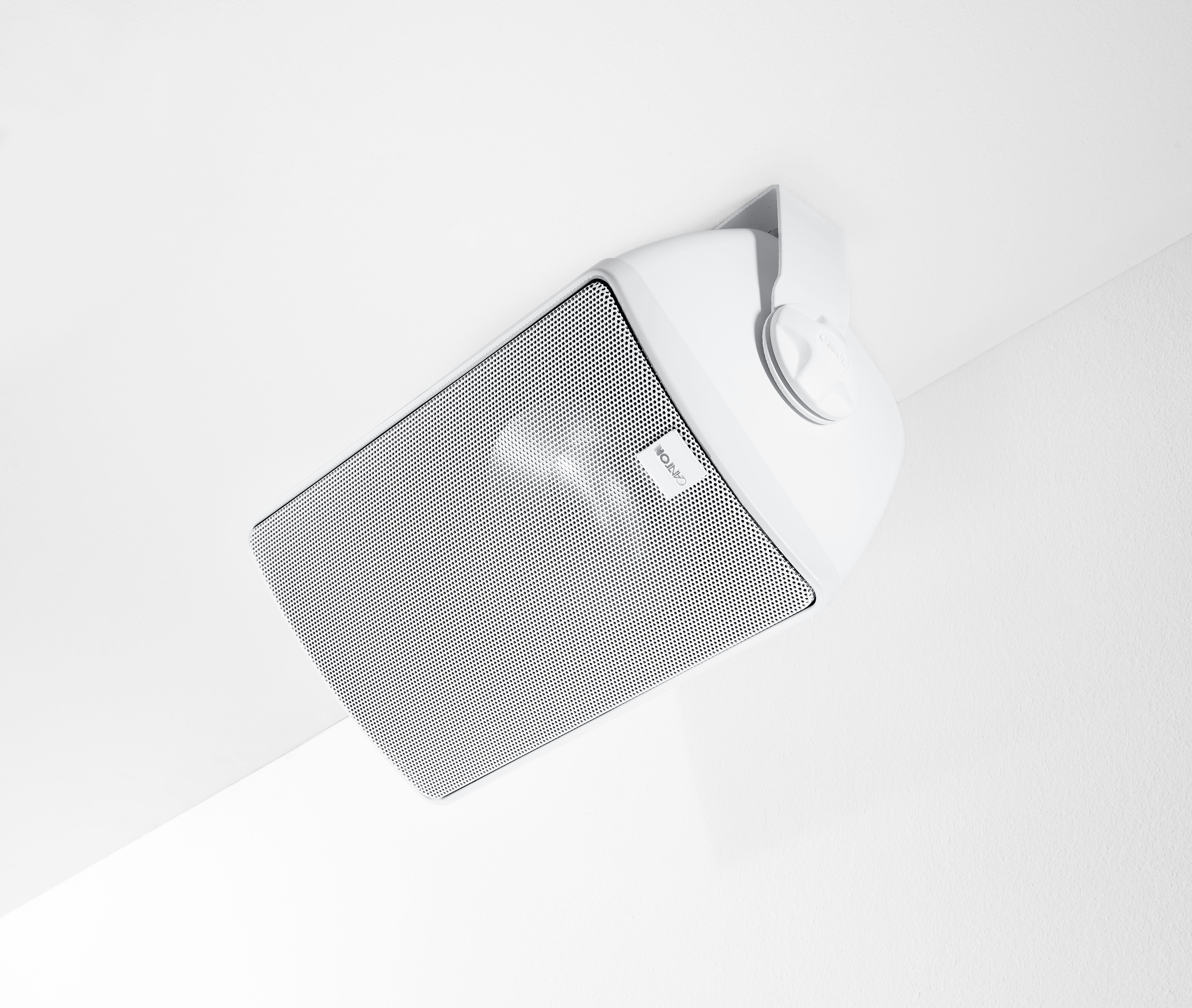 Weißer, an der Decke montierter Lautsprecher mit schwarzer Gitterfront. Winkelansicht, sauberer, weißer Hintergrund.