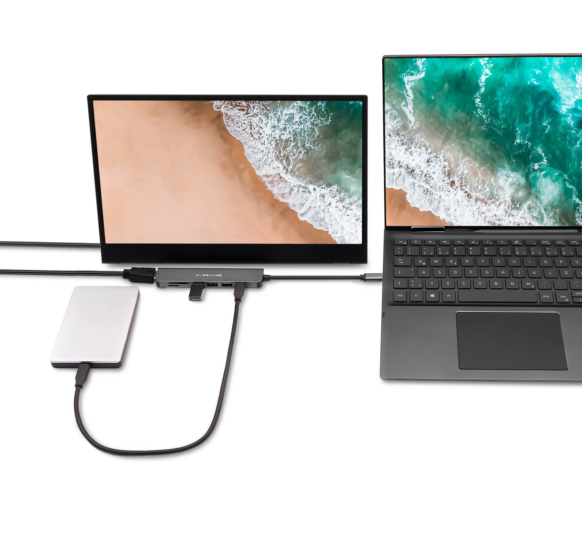 Laptop, externer Monitor und Festplatte, verbunden über einen Hub. Zeigt Strand- und Ozeanbilder.
