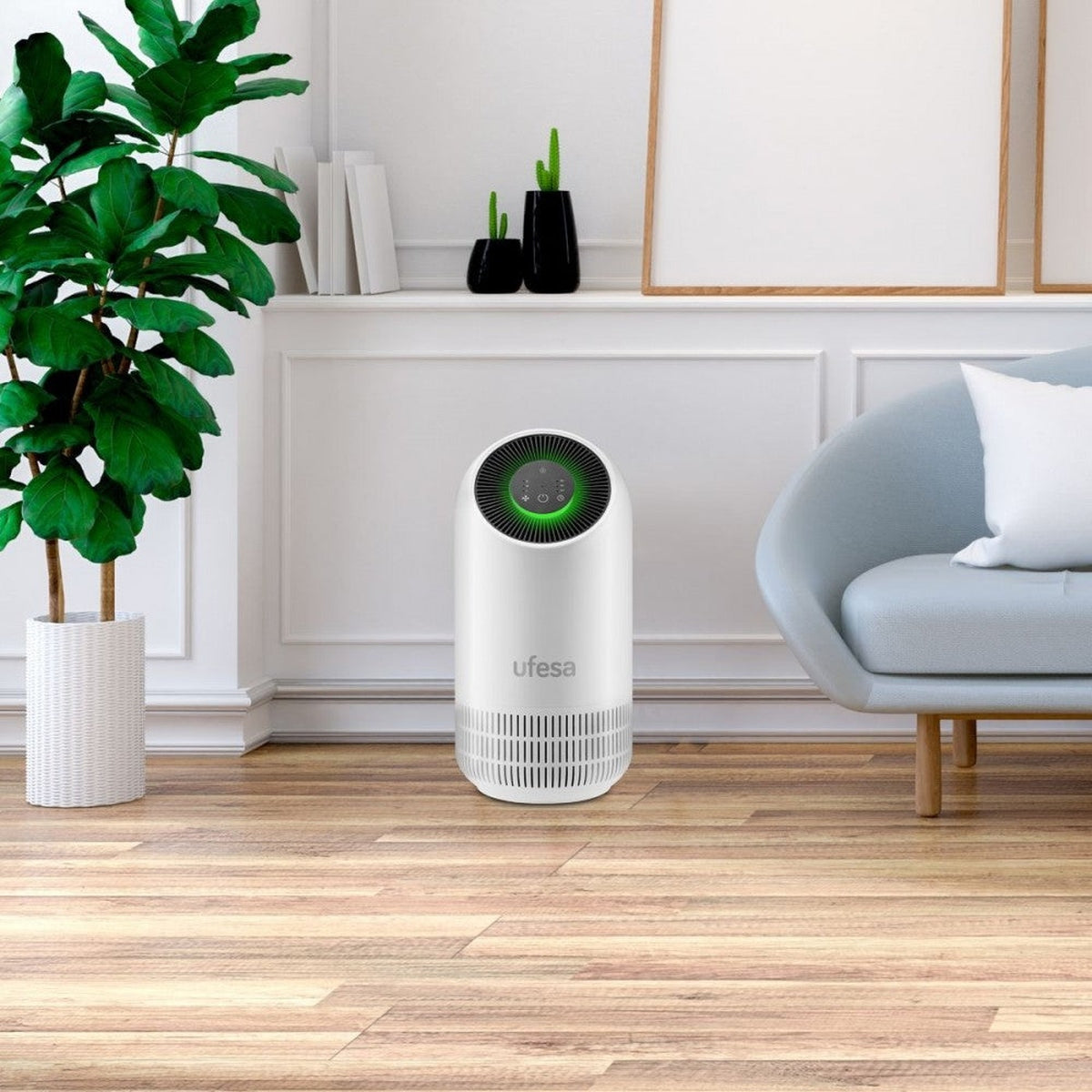 Purificatore d'aria bianco in una stanza con una pianta, una sedia e un pavimento in legno. Le pareti sono bianche.