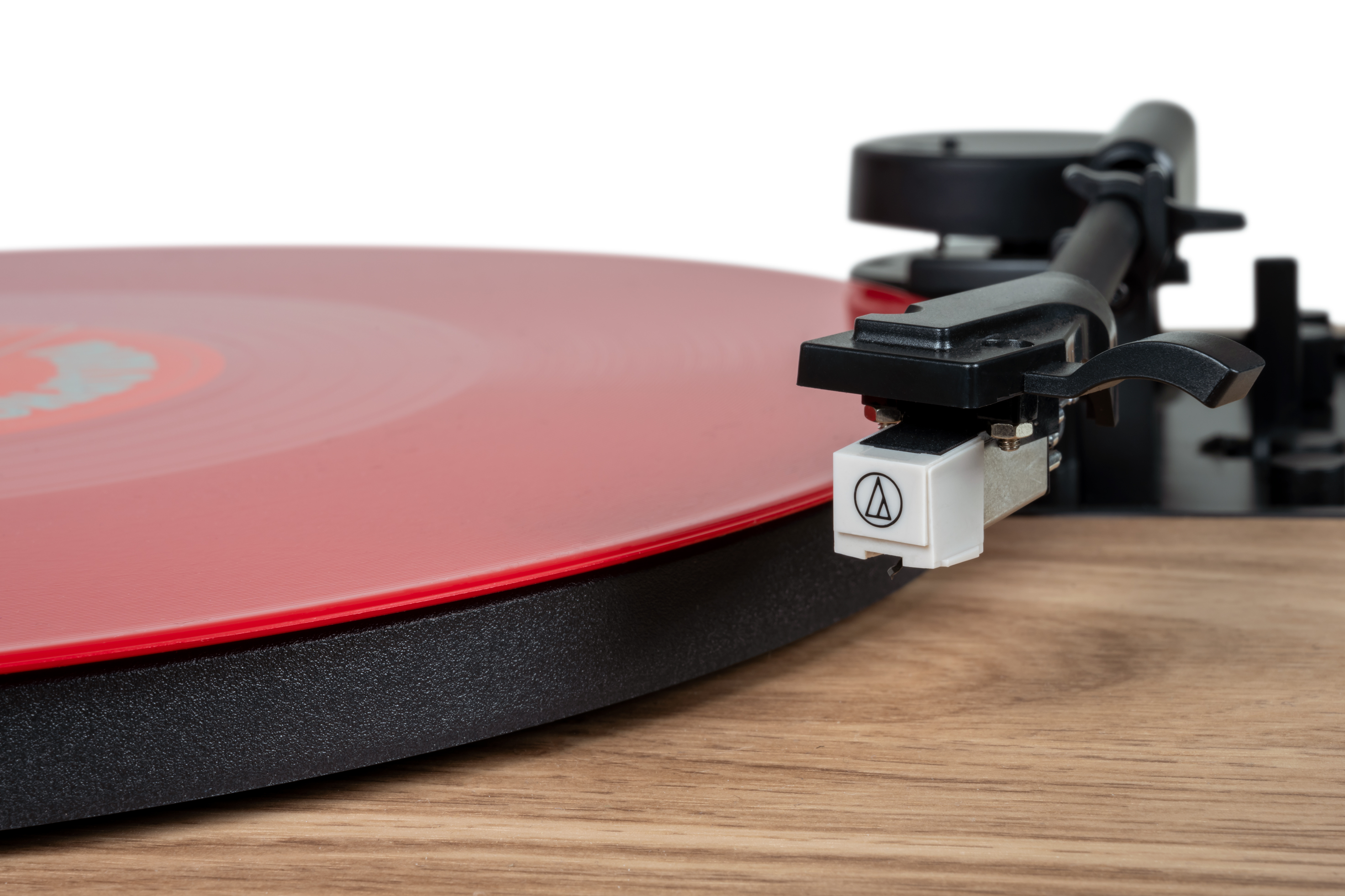 Gramofon z czerwoną płytą winylową na drewnie. Igła jest blisko płyty.