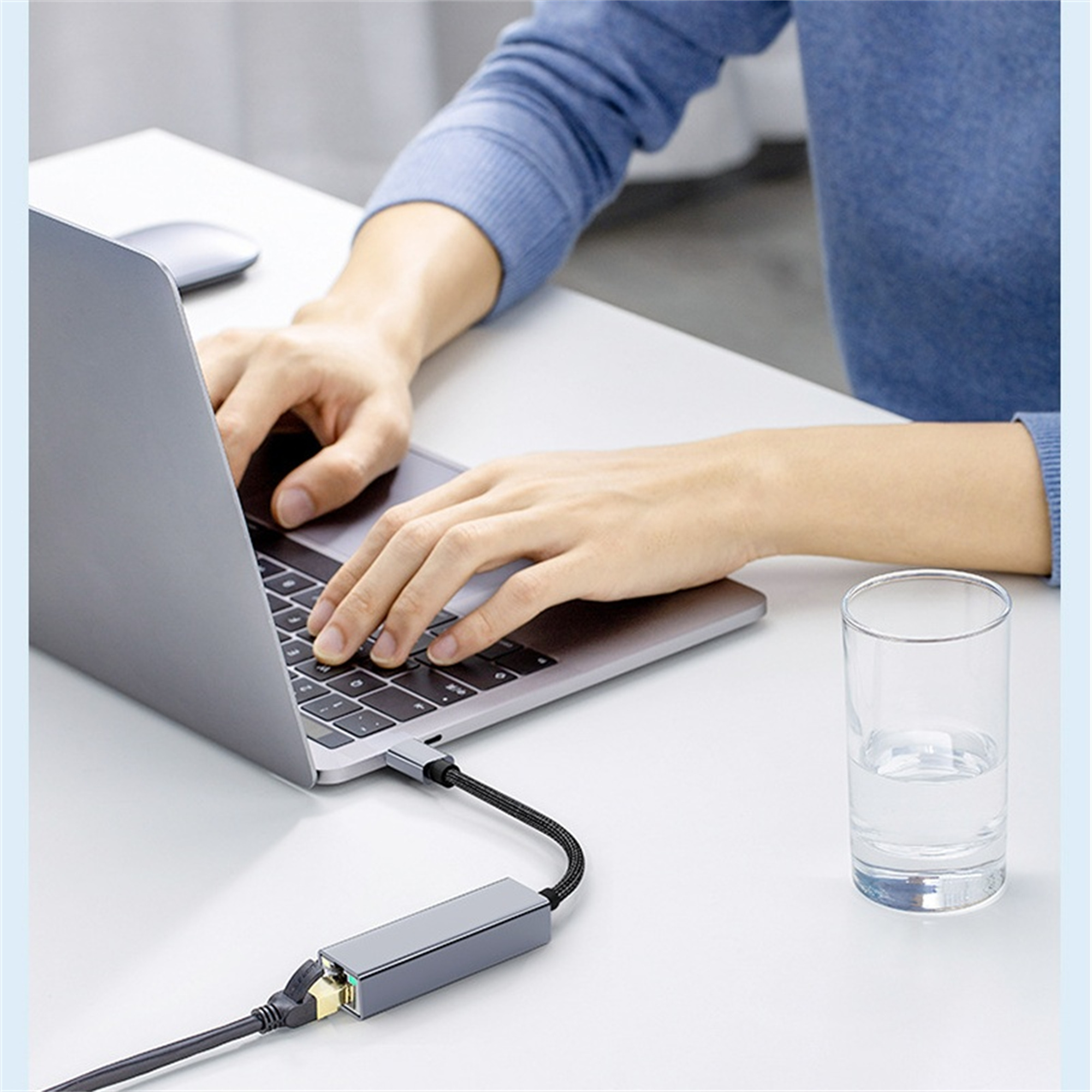 Person benutzt Laptop, verbunden mit silbernem Adapter mit schwarzem Kabel.